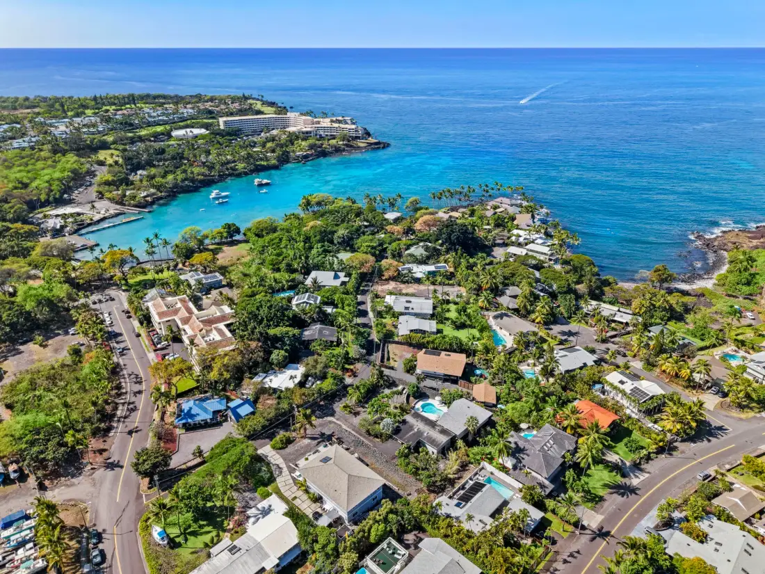 Aerial view of a coastal neighborhood surrounded by greenery and blue water.