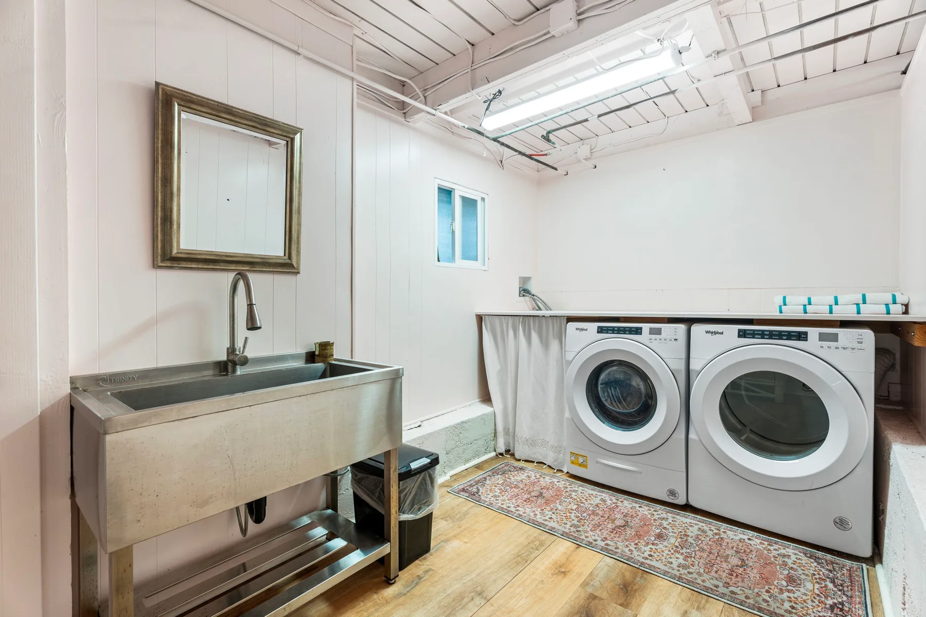 A laundry room with front-loading washing machines and a utility sink.