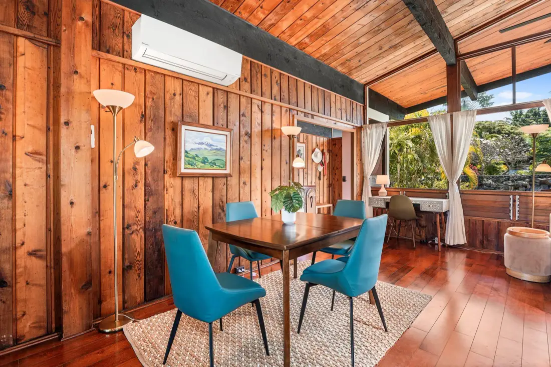 A wood-paneled dining area with a table, chairs, and large windows.