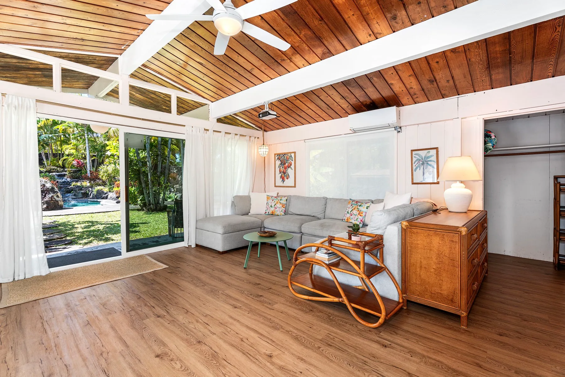 A bright living room with seating beside large glass doors opening onto a garden.