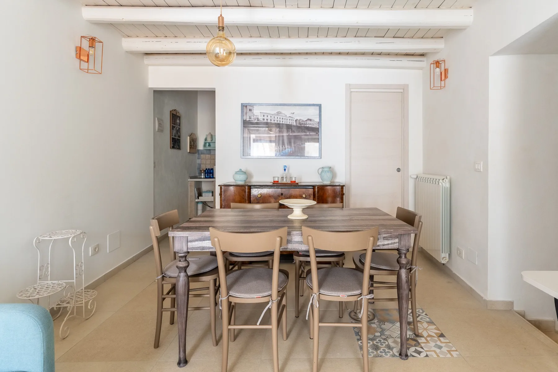 Comedor con una mesa larga de madera y sillas bajo vigas expuestas en el techo.