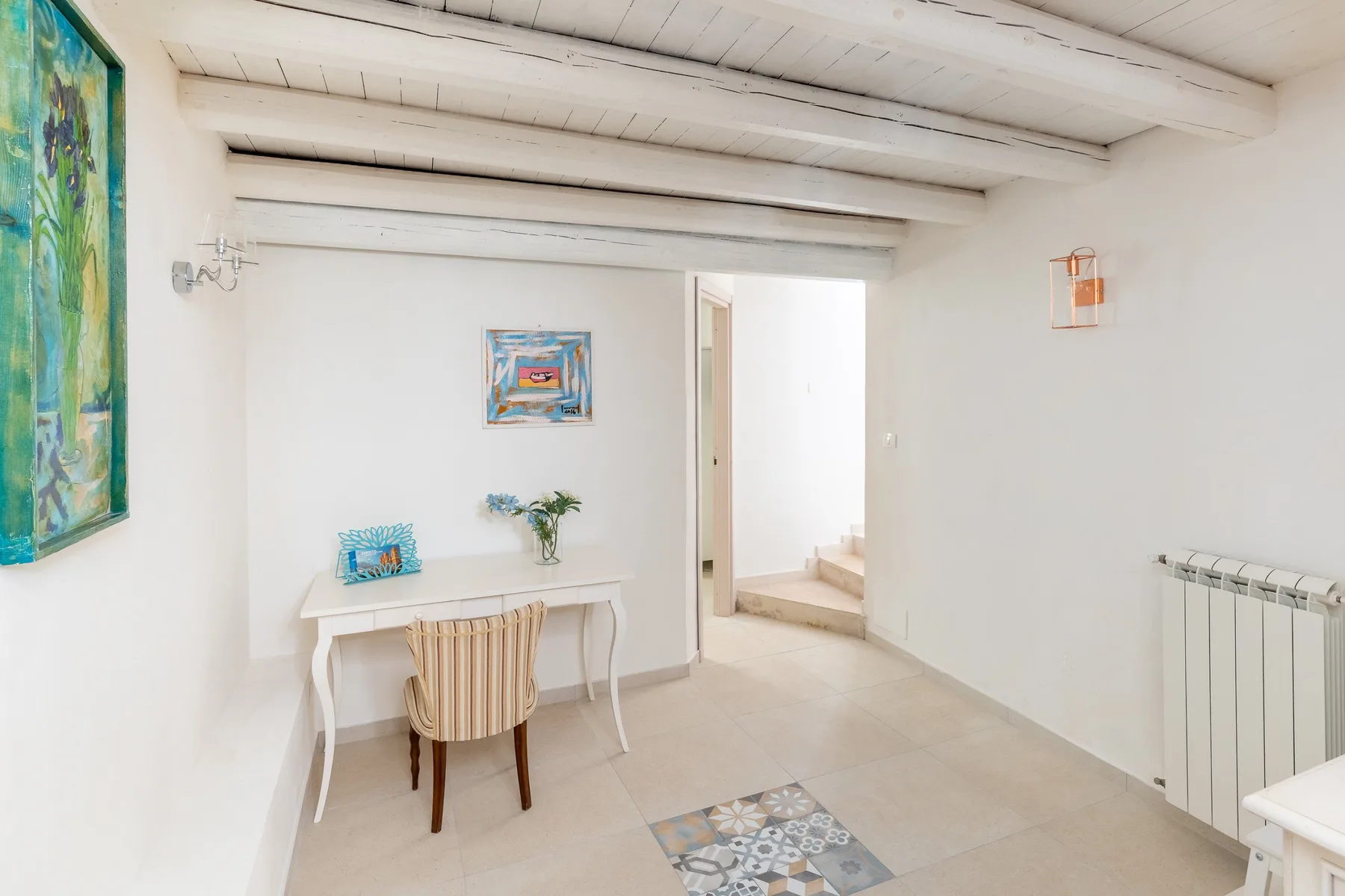 Una habitación luminosa con escritorio, silla y obras de arte en las paredes.