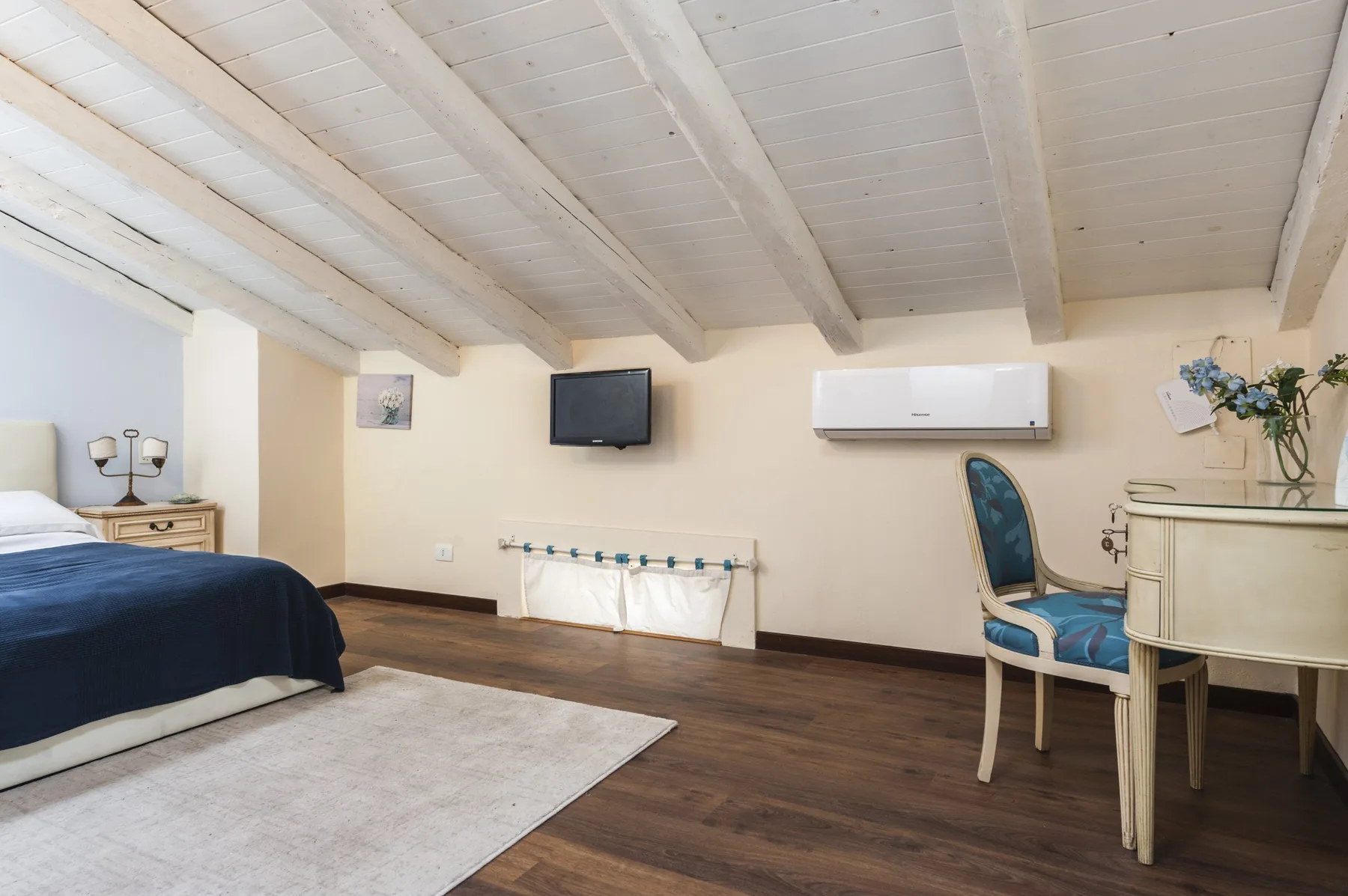 Un dormitorio con una cama, un televisor en la pared y un escritorio.