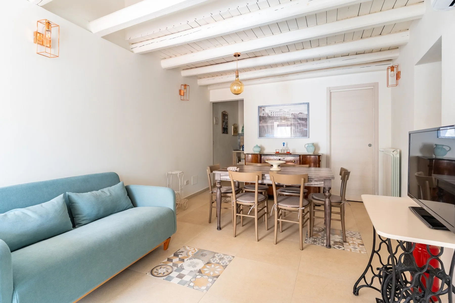 Una luminosa sala de estar y comedor con un sofá verde azulado y una mesa de comedor.