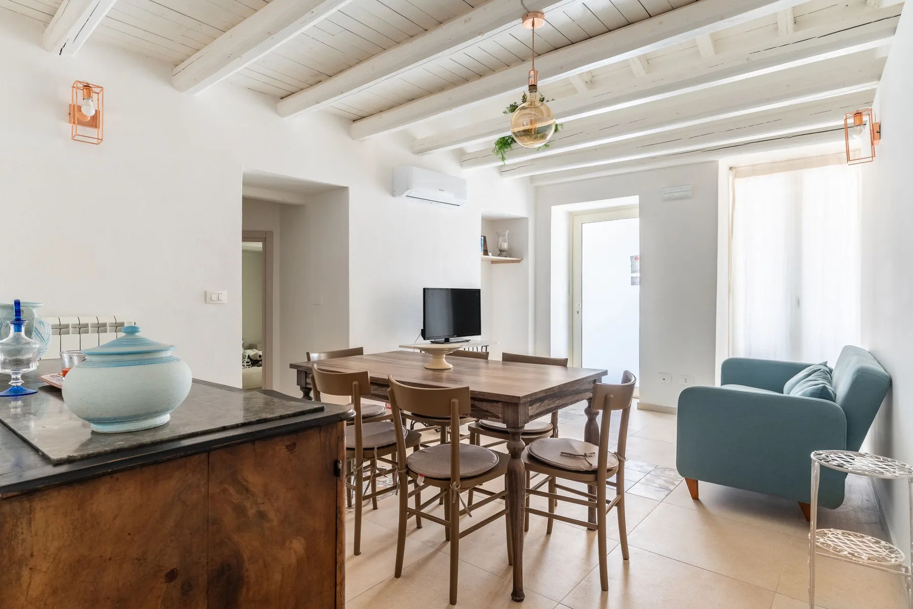 Un comedor luminoso con una mesa de madera y asientos junto a una zona de estar.