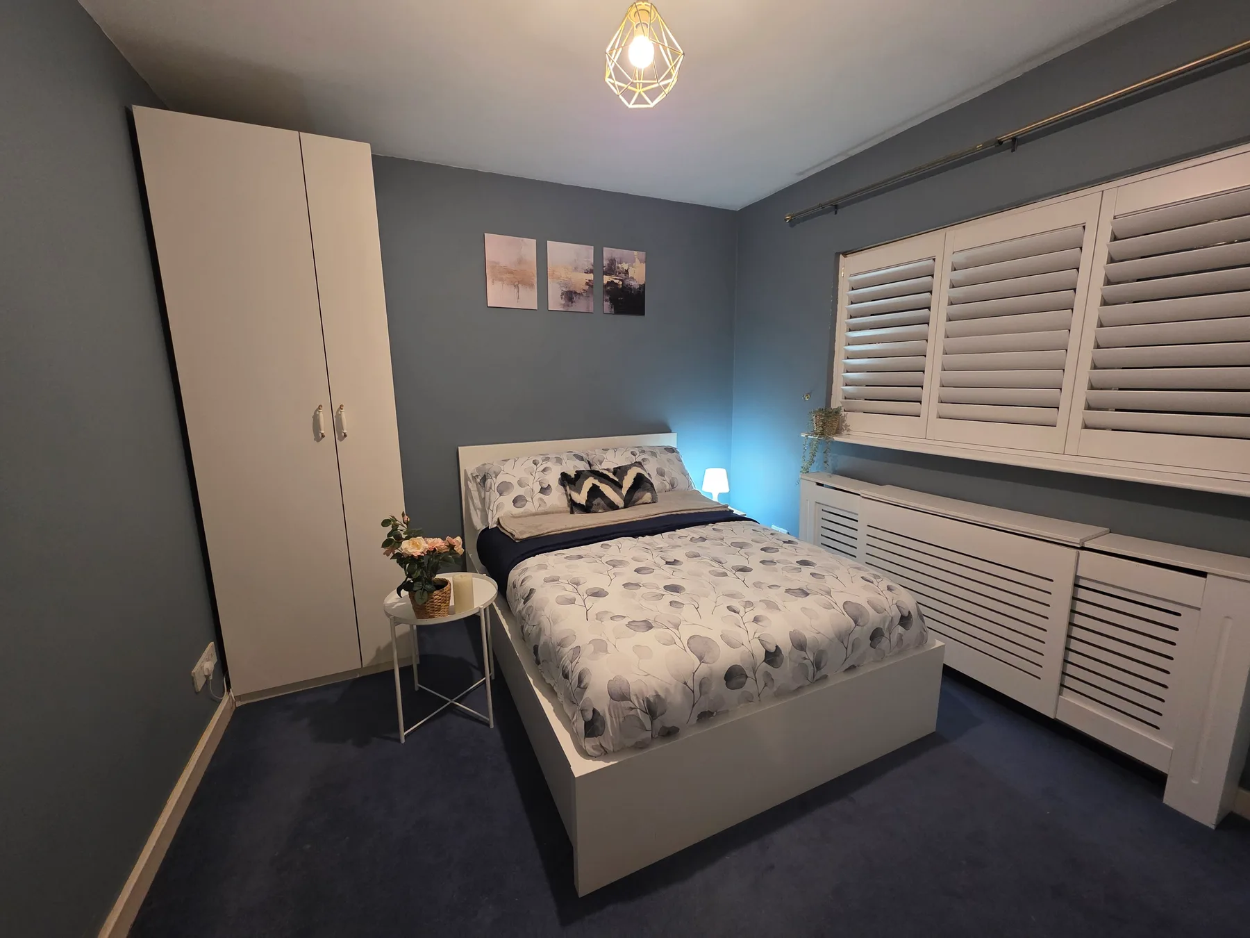 A bedroom with a bed, a wardrobe, and shuttered windows.