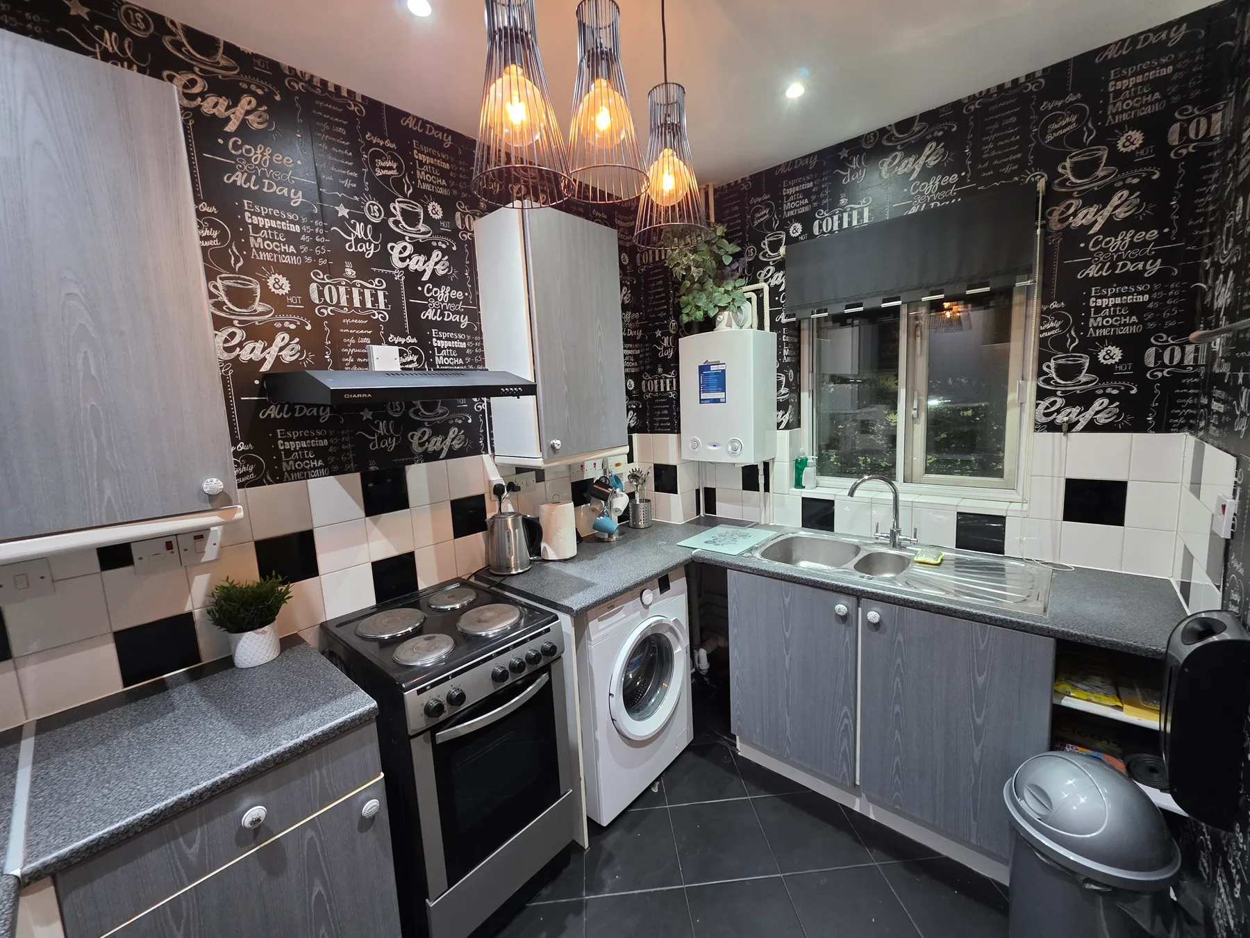 A compact kitchen with gray cabinets, a stove, and a sink.