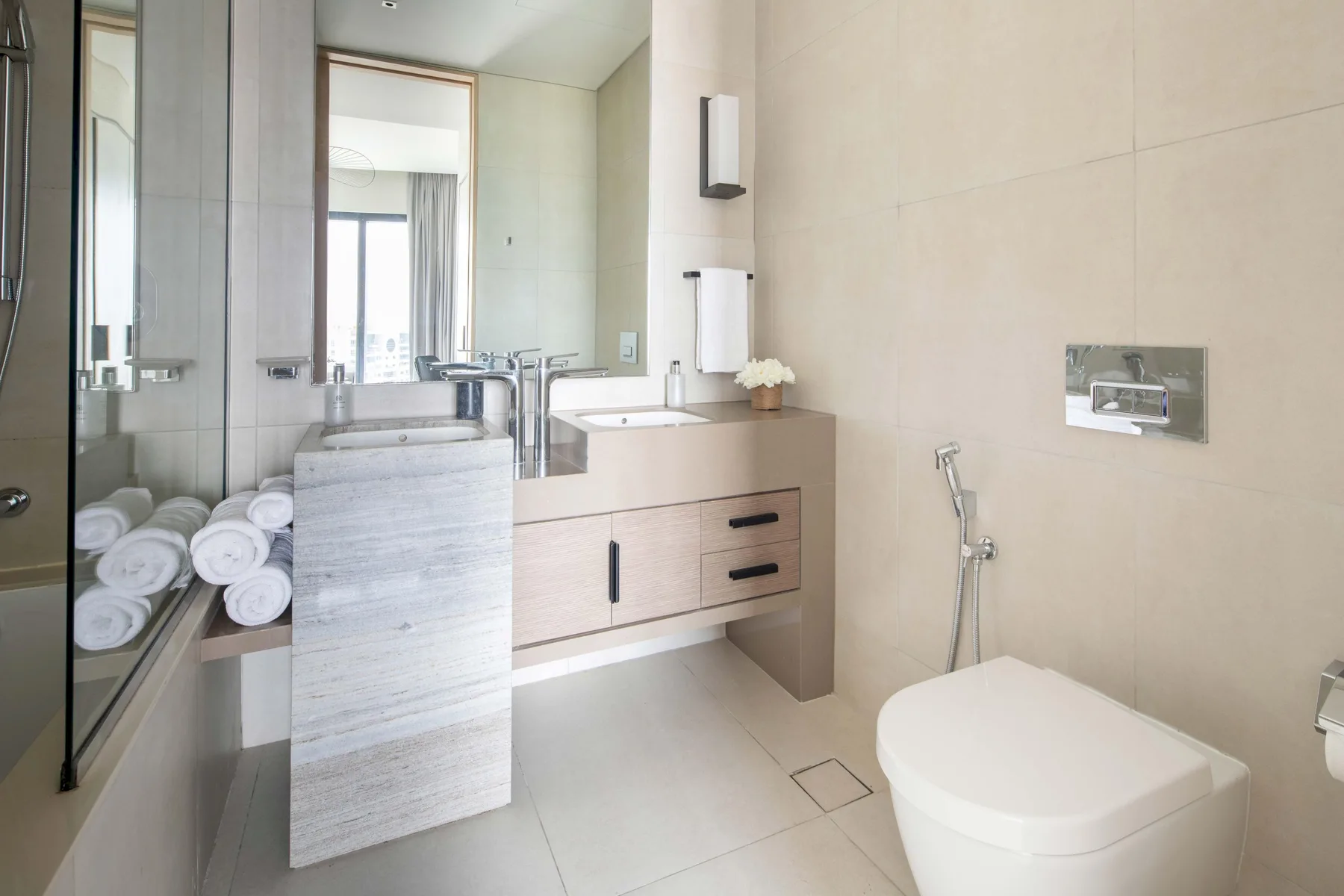 Un baño luminoso con lavabo, espejo, inodoro y ducha de mano.