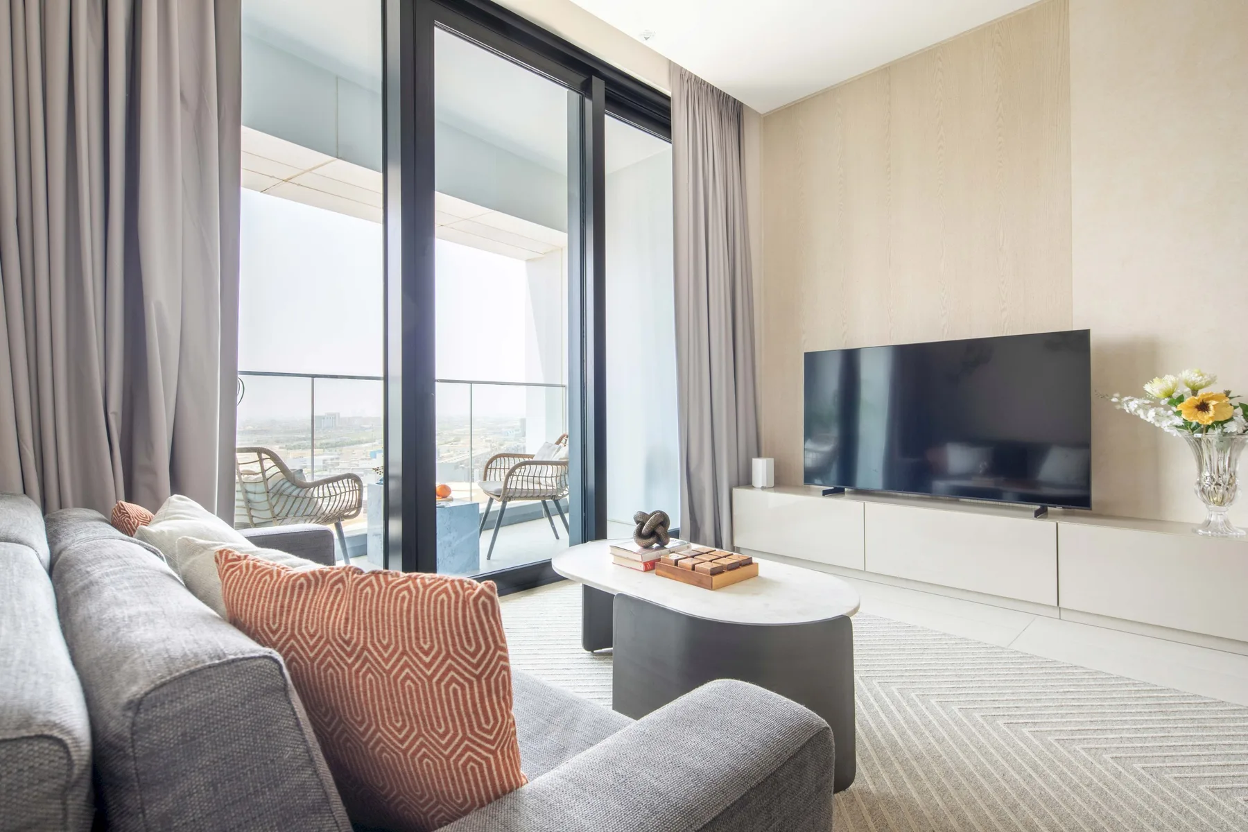 A bright living room with seating, a television, and large glass doors.