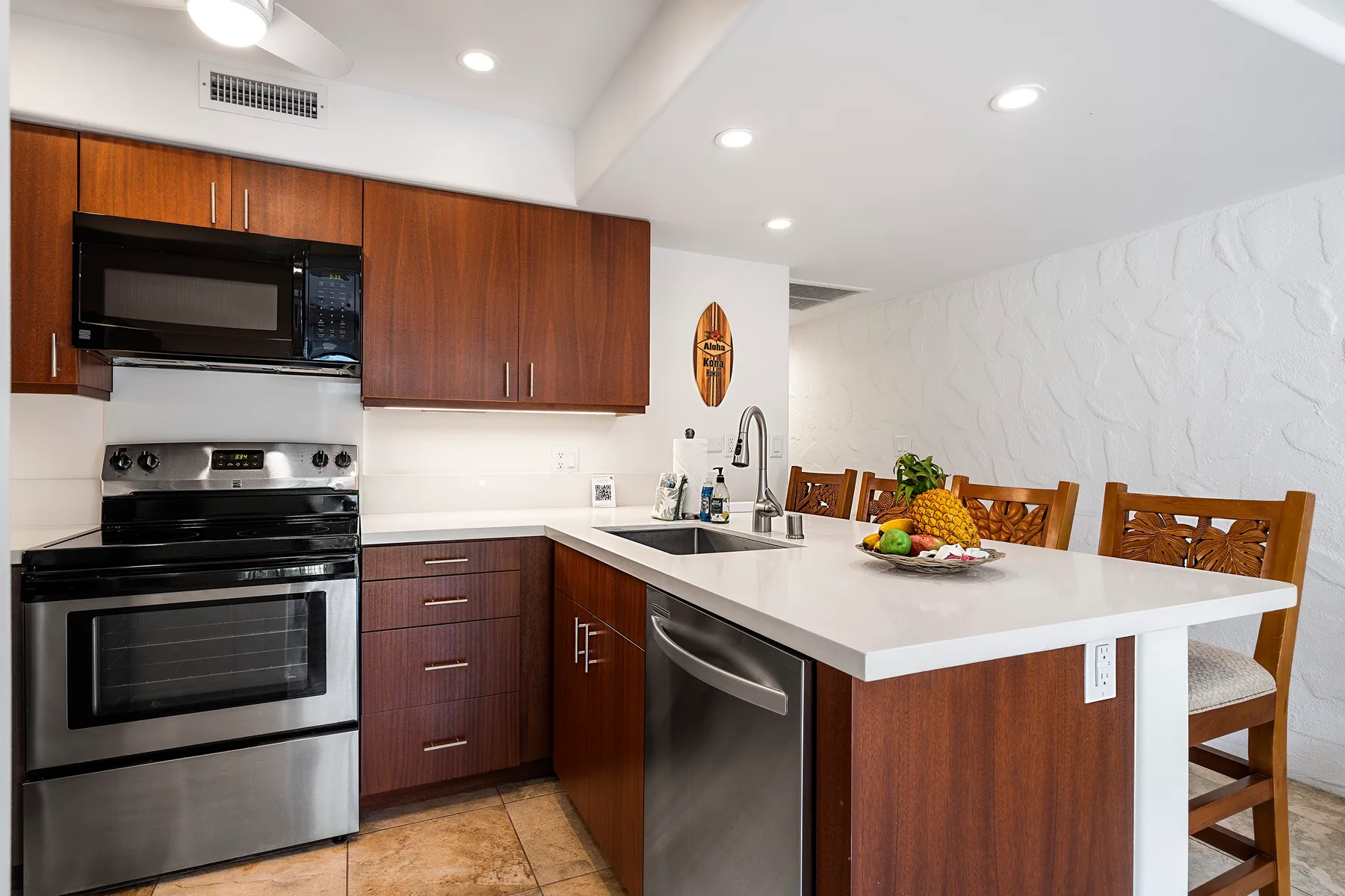 Una cocina con gabinetes de madera, electrodomésticos de acero inoxidable y una barra para comer.