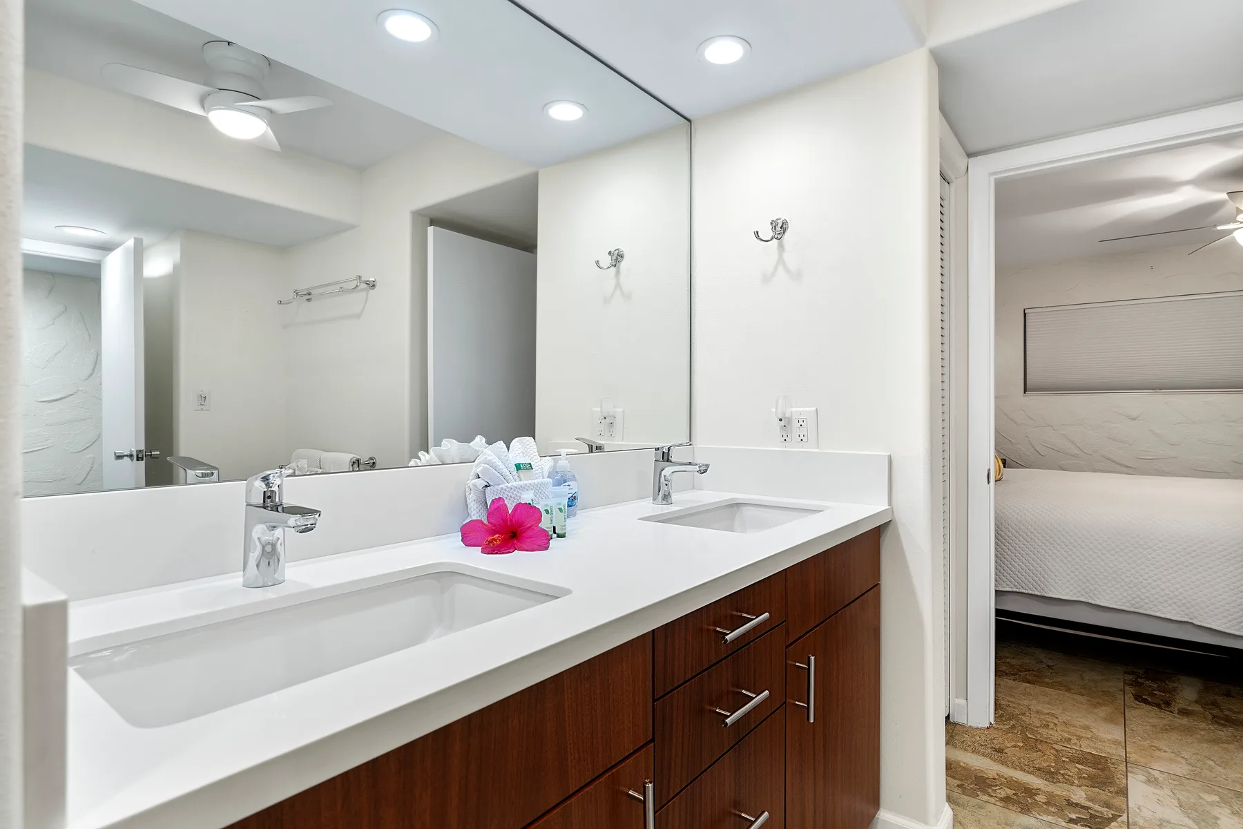 Un lavabo de baño luminoso con un espejo grande y un lavamanos blanco.