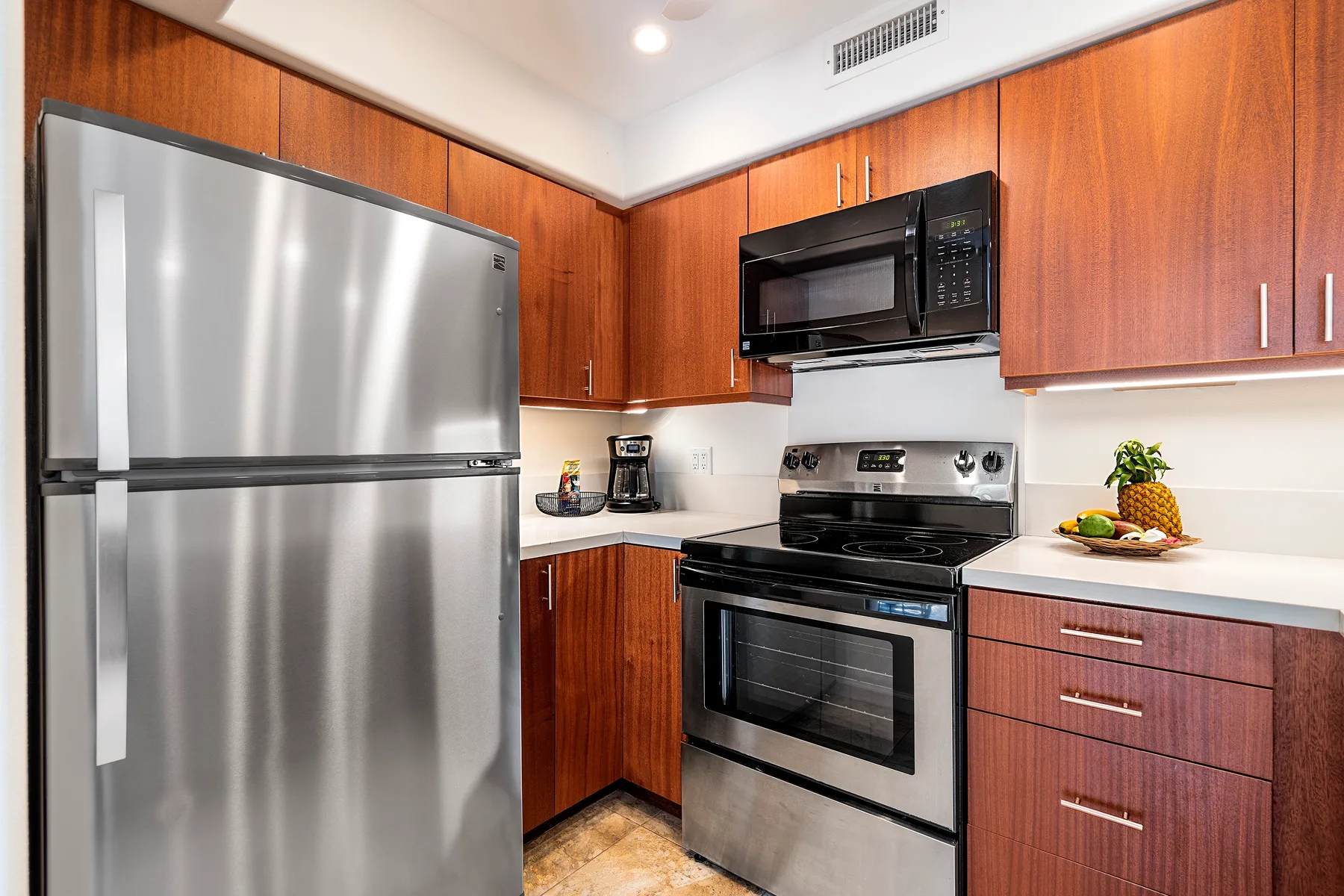 Una cocina con refrigerador de acero inoxidable, estufa y gabinetes de madera.