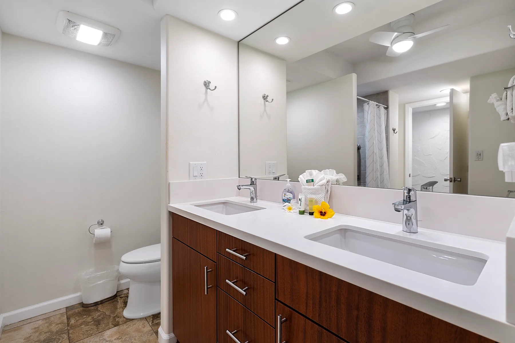 Un baño luminoso con un tocador largo, lavabo y espejo grande.