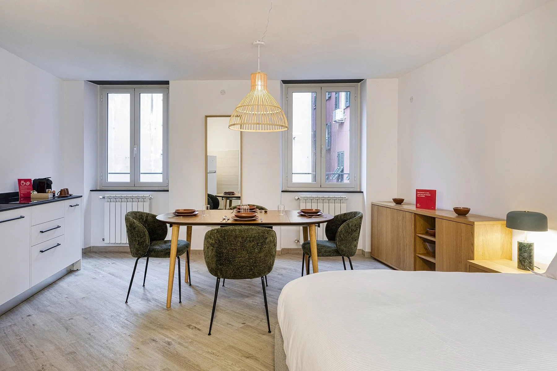 Un comedor luminoso con una mesa de madera y varias sillas junto a una cama.