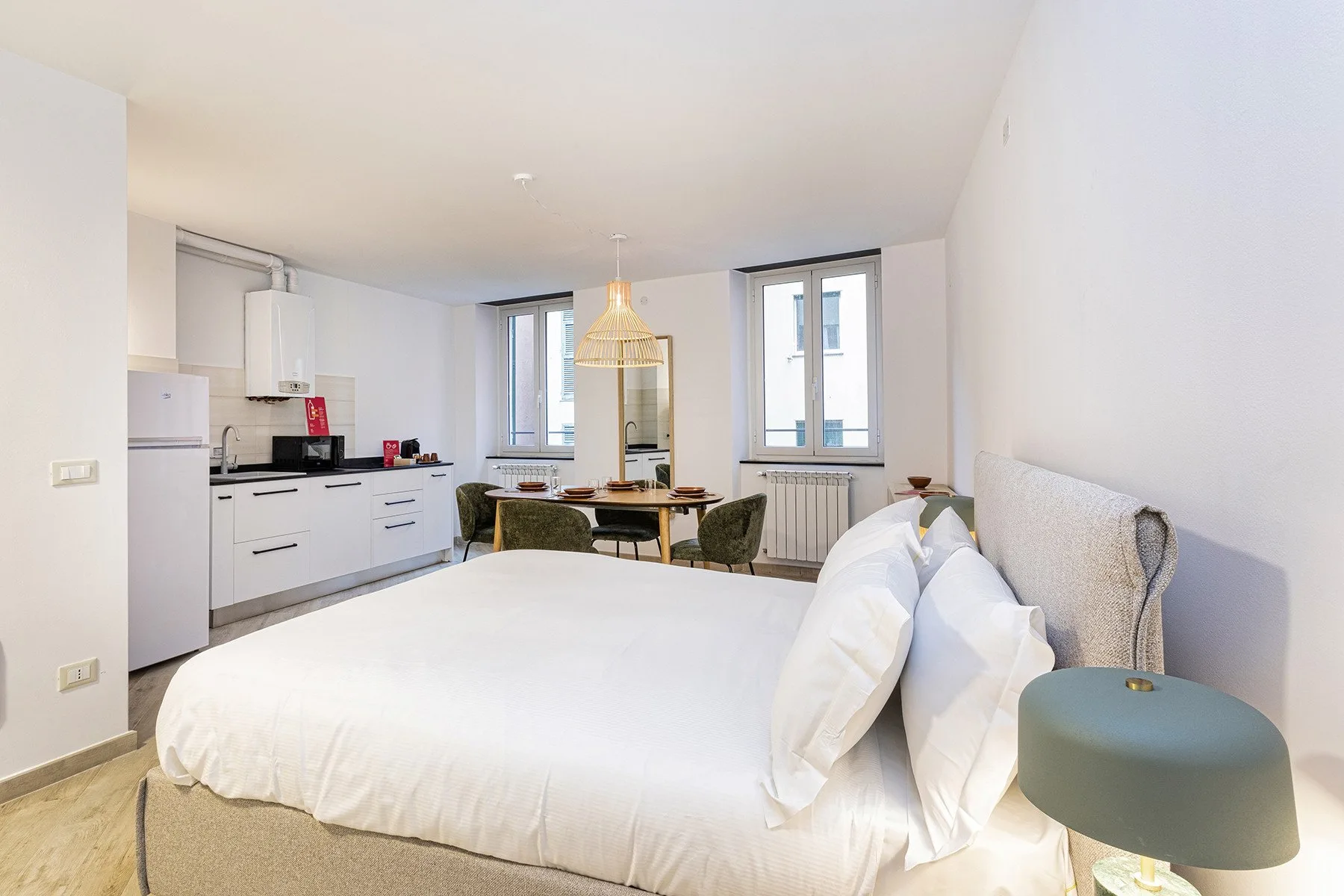 Un dormitorio luminoso con una cama grande y una pequeña cocina junto a la pared.