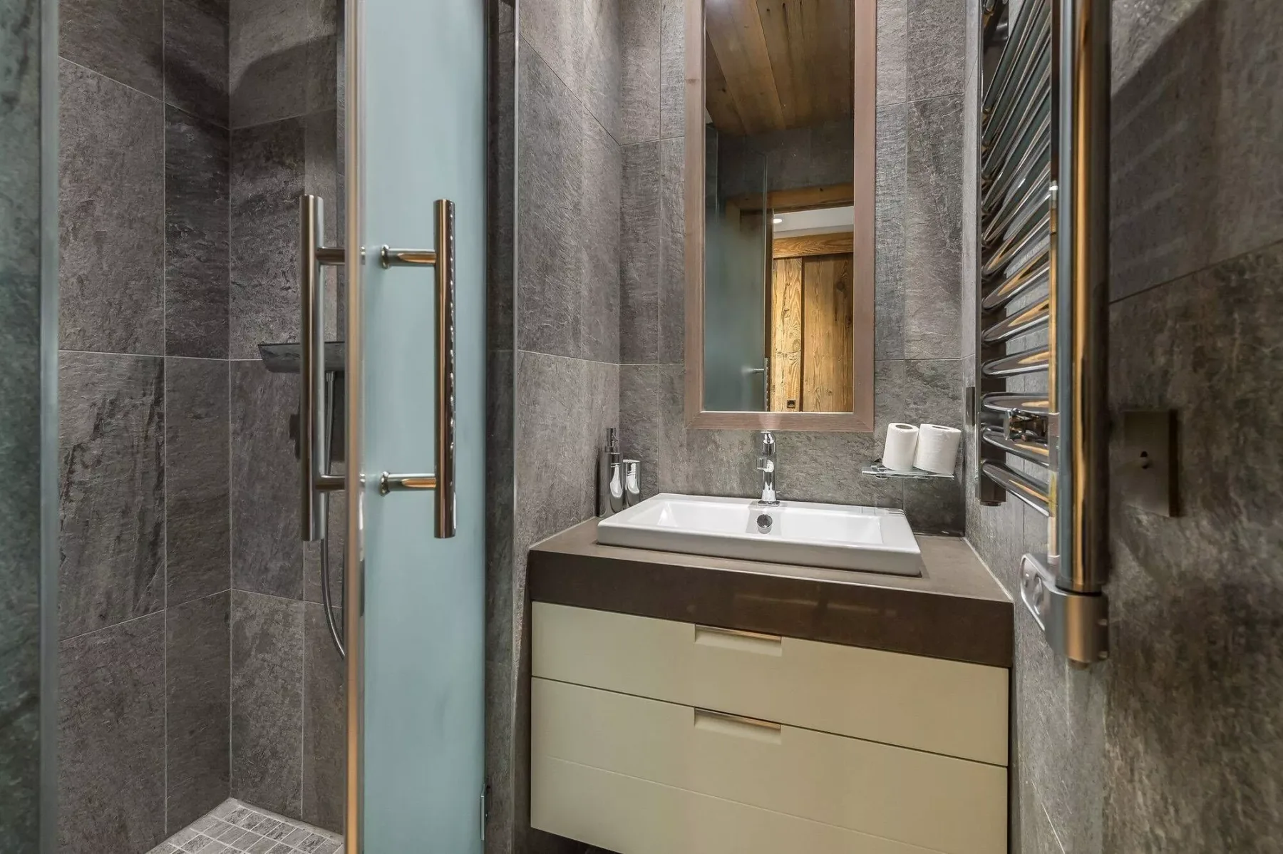 A modern bathroom with a sink, mirror, and glass shower.