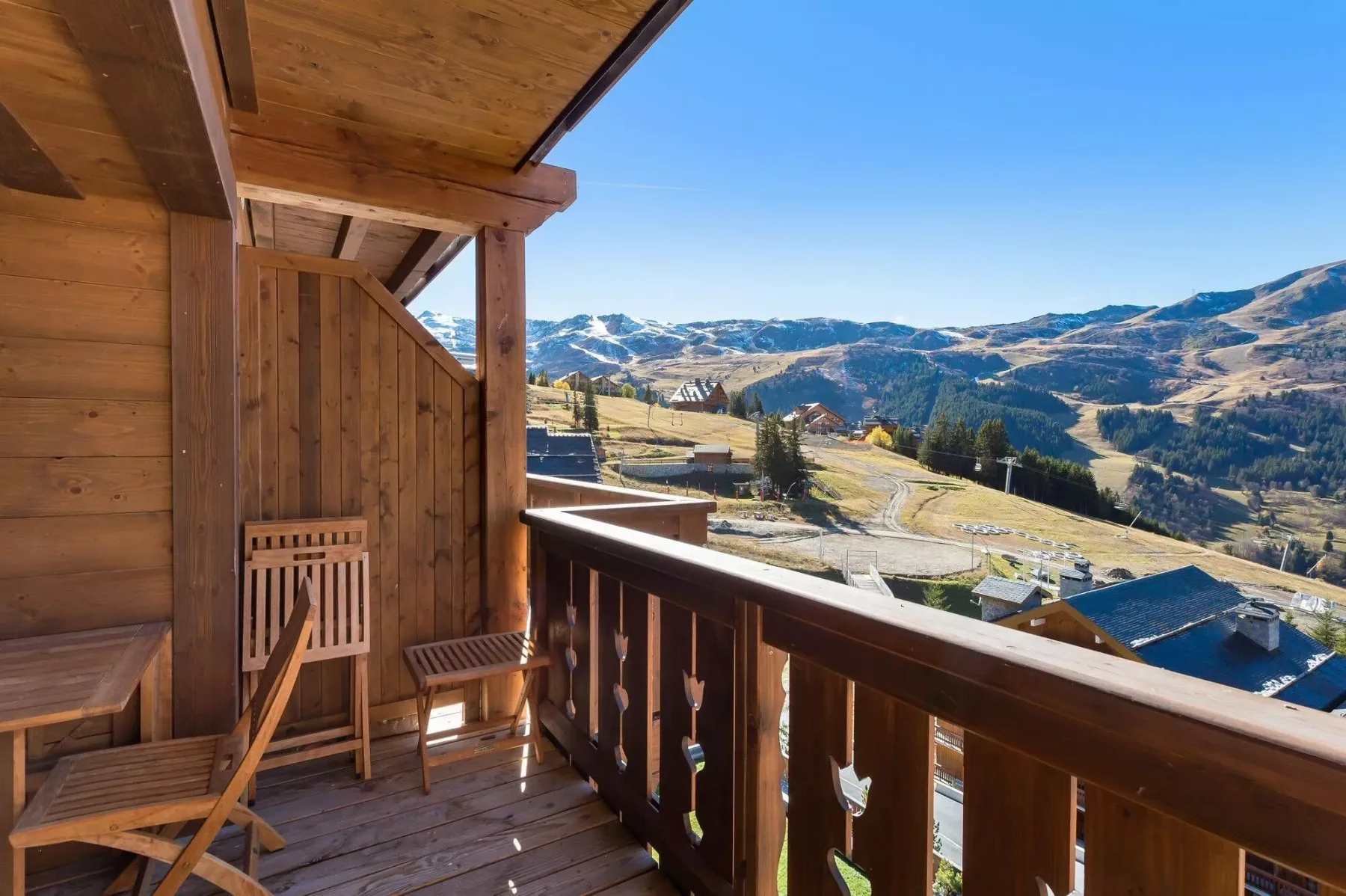 A wooden balcony overlooks a mountain landscape and winding valley roads.