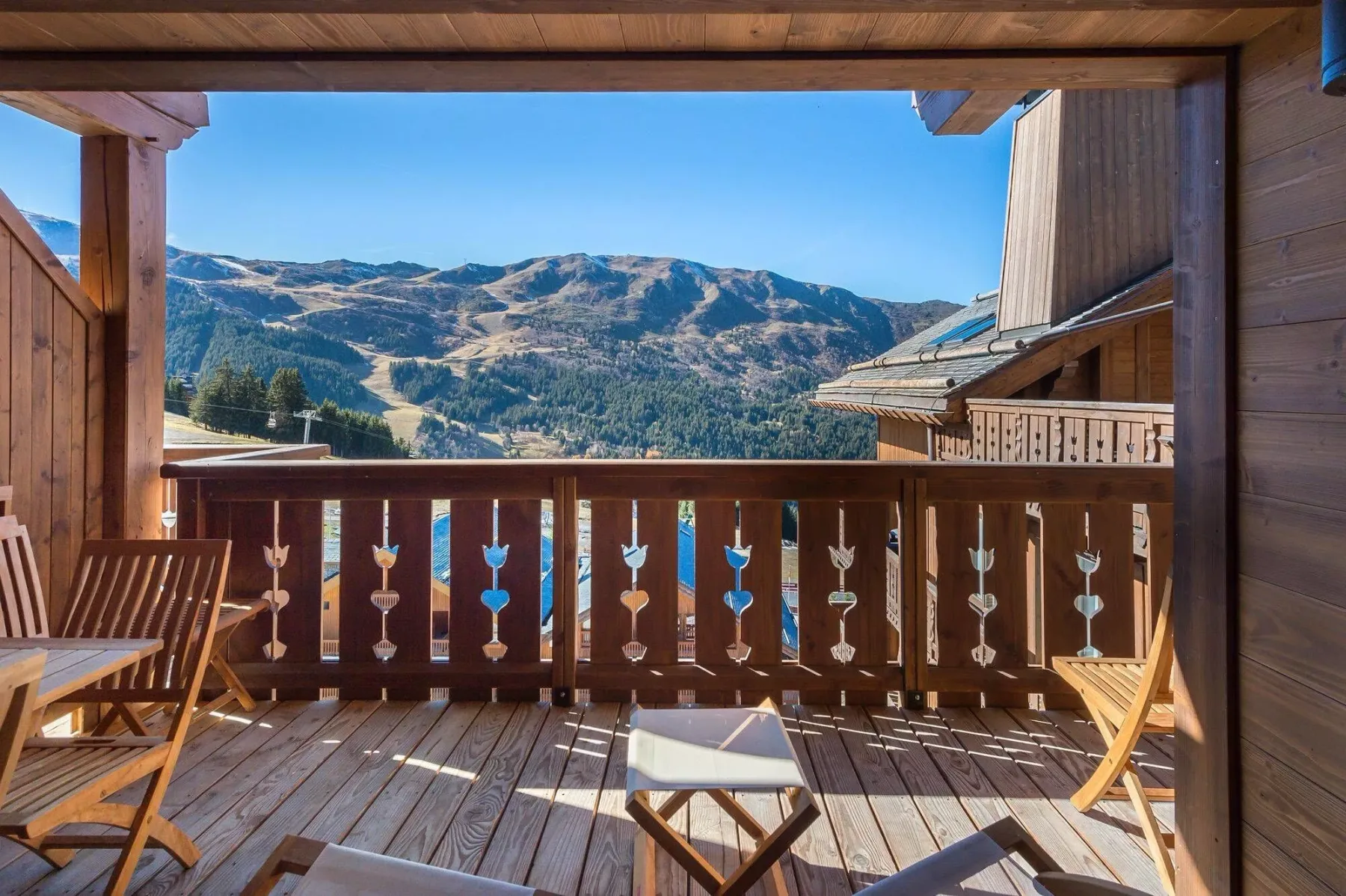 A wooden balcony with seating overlooks a mountain landscape.