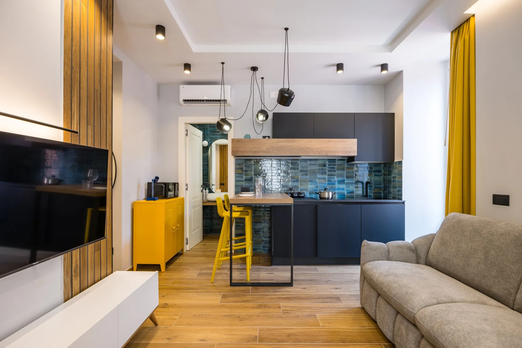 A modern open-plan living room and kitchen with a breakfast bar and seating.