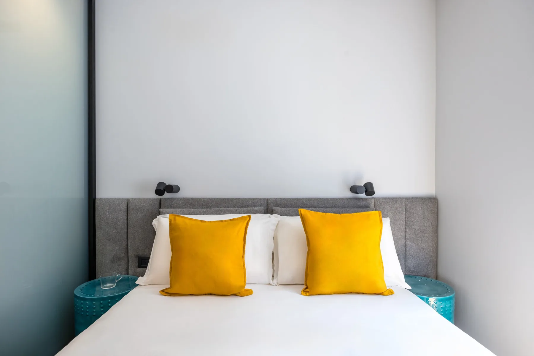 A bedroom with a white bed and bright yellow pillows.