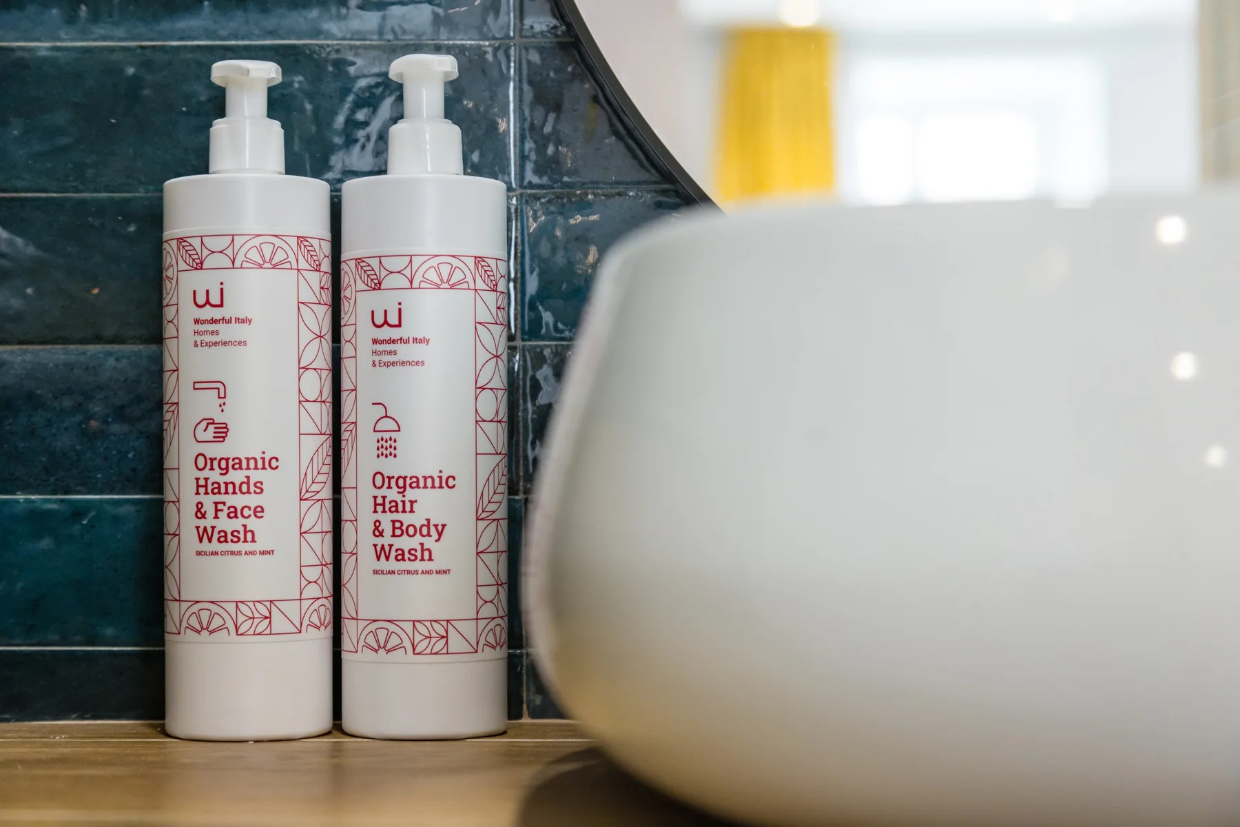 Bathroom toiletries sit beside a sink against a dark tiled wall.