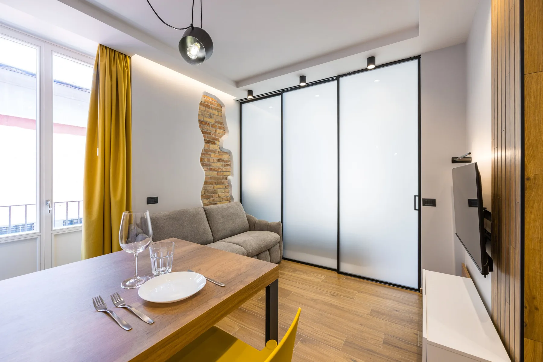 A living and dining area with a sofa, a set table, and frosted glass doors.