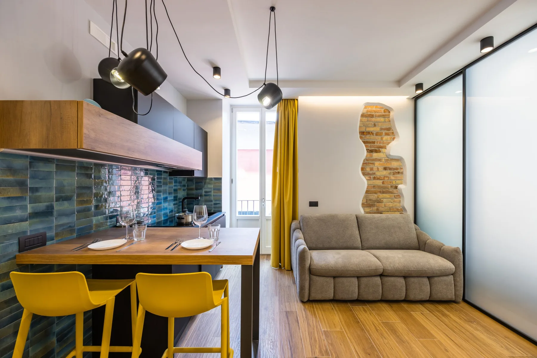 A modern dining and sitting area with a table beside a small sofa.