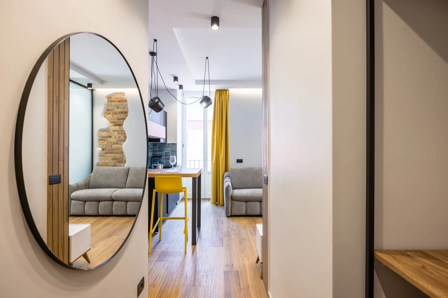 A bright living area with seating, a dining counter, and yellow curtains.
