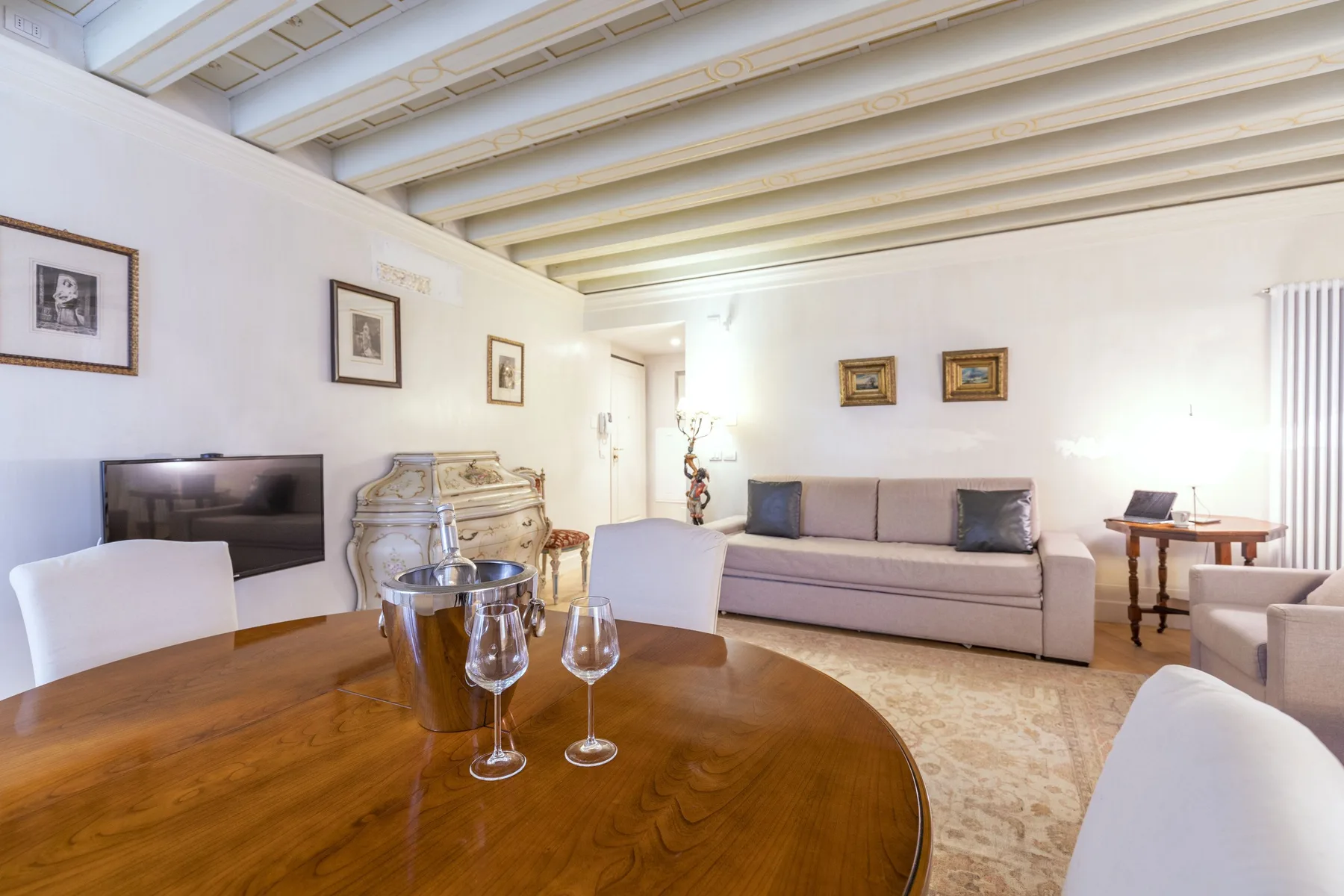 A living room with a dining table in the foreground and seating along the wall.