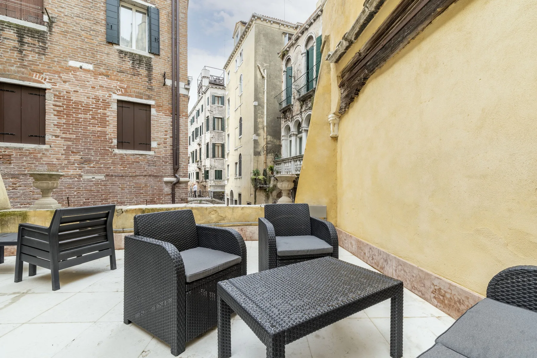 An outdoor courtyard seating area with dark woven chairs and a low table.