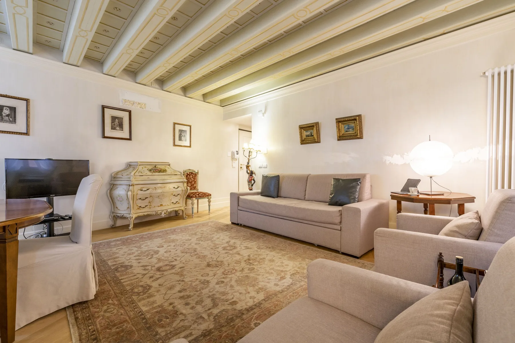A living room with a sofa, armchairs, and a patterned rug.