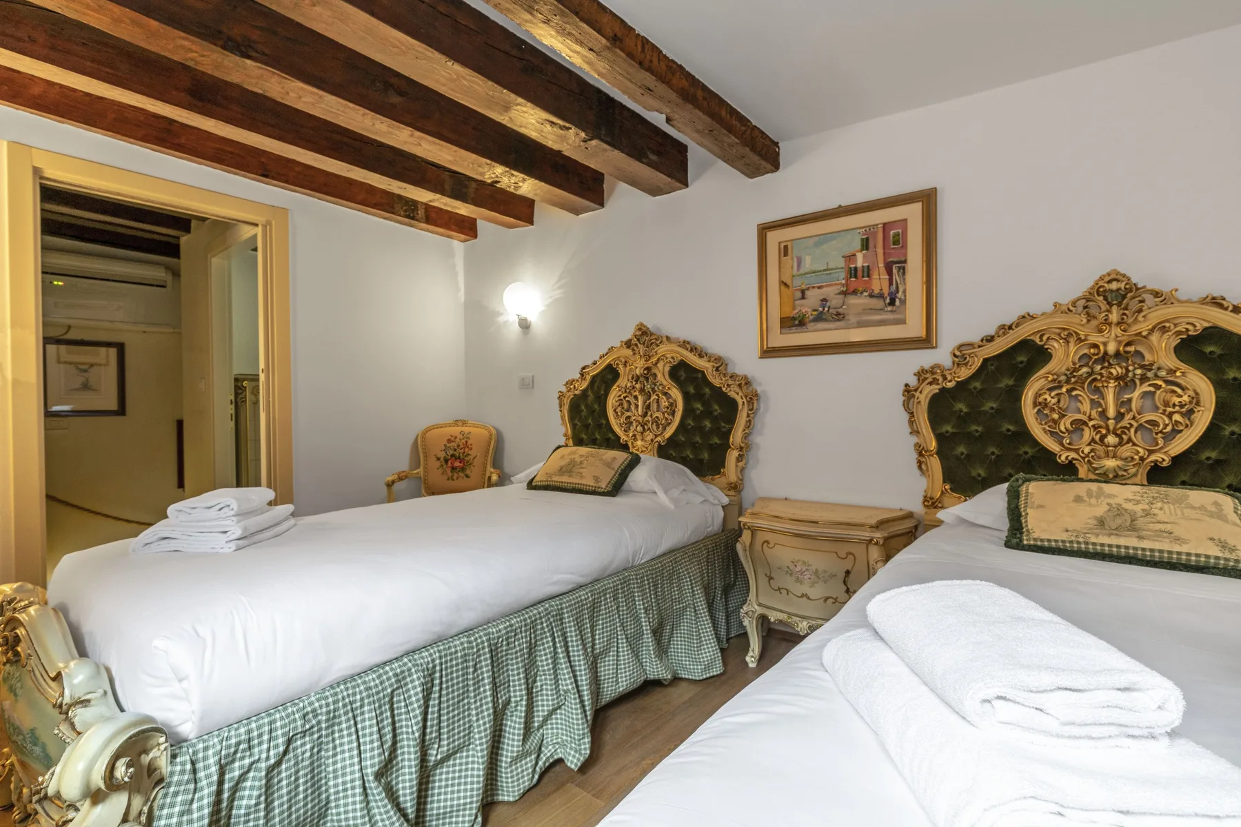 A bedroom with two beds, ornate headboards, and exposed ceiling beams.