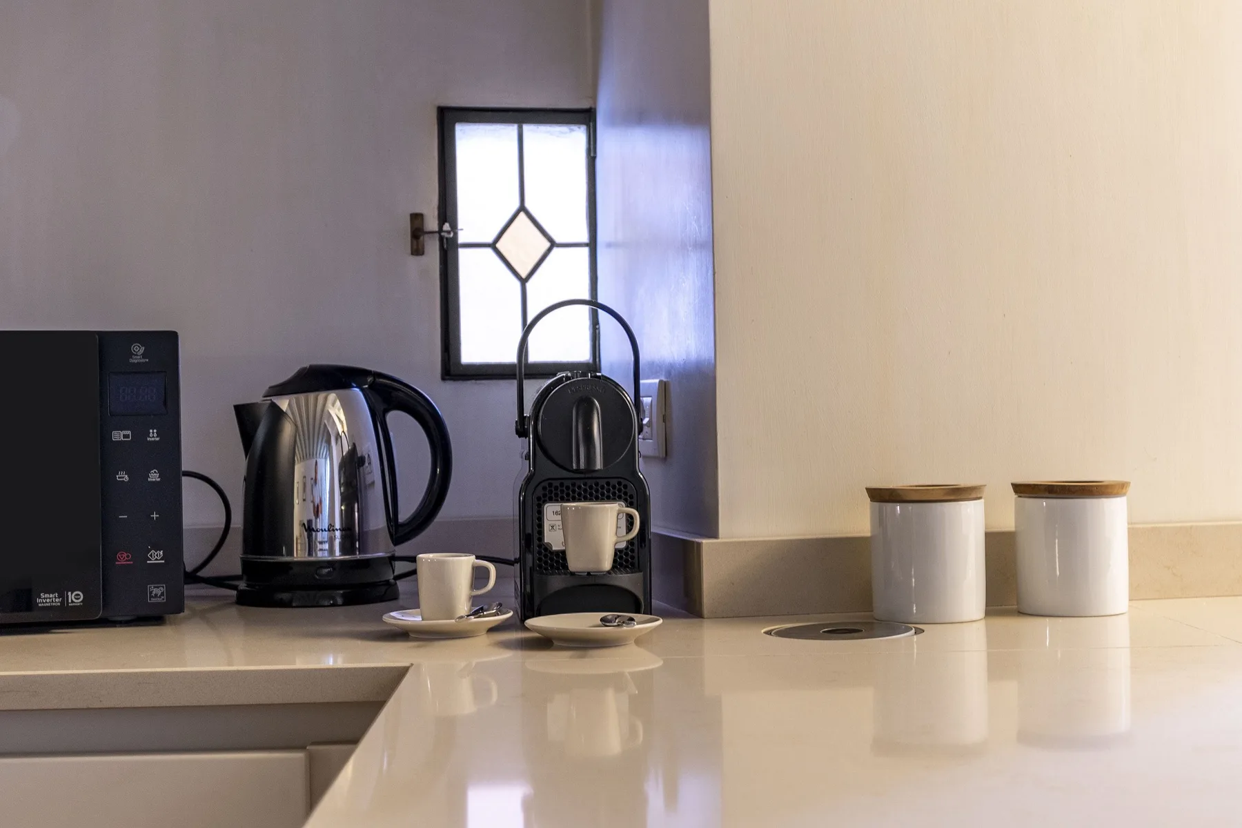 A kitchen counter with a kettle, coffee machine, and two canisters.