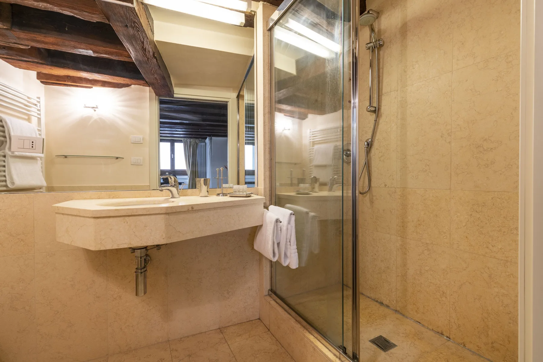 A bathroom with a wall-mounted sink and glass shower.