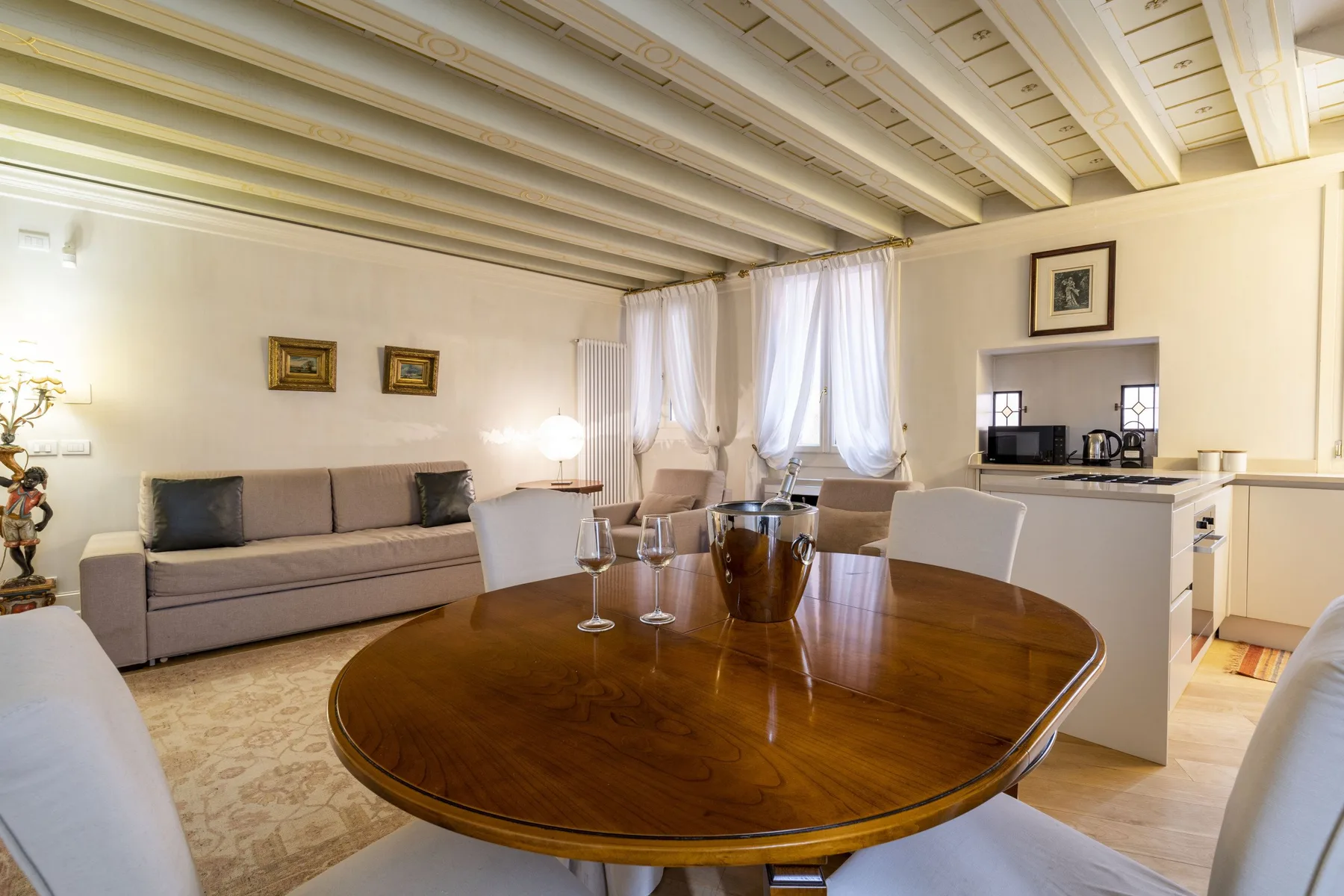 A dining area with a round wooden table and seating beside a living room.