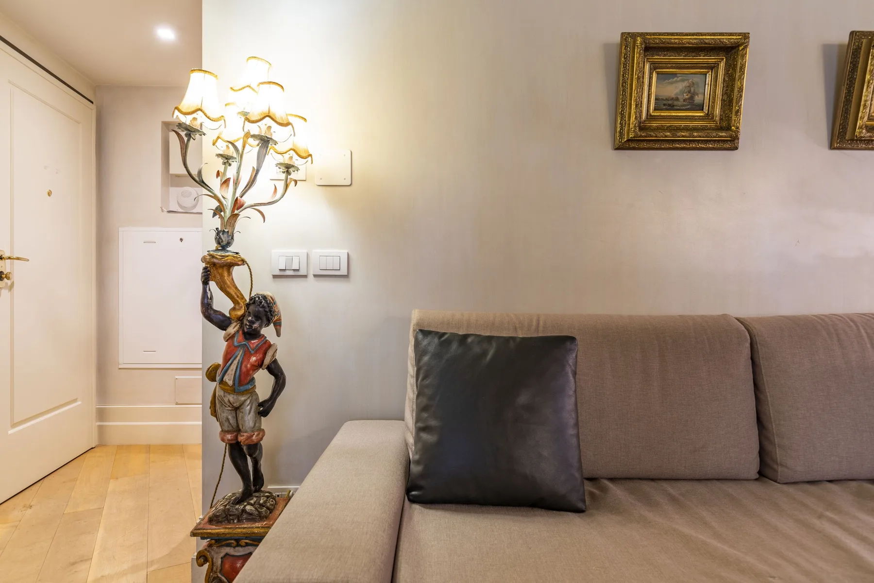 A living room with a sofa, dark cushion, and decorative floor lamp.