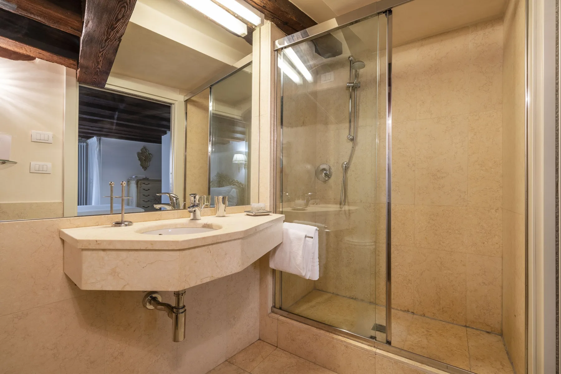 A bathroom with a wall-mounted sink and glass-enclosed shower.