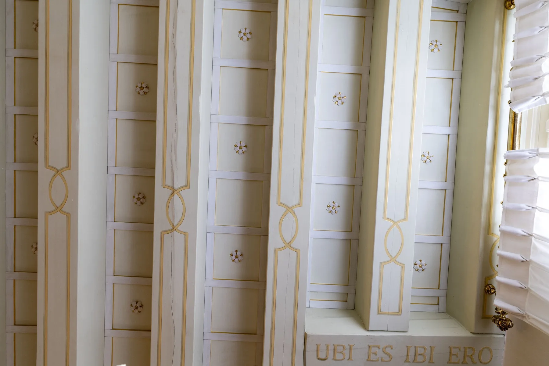 A bright interior wall features tall decorative panels beside a window.