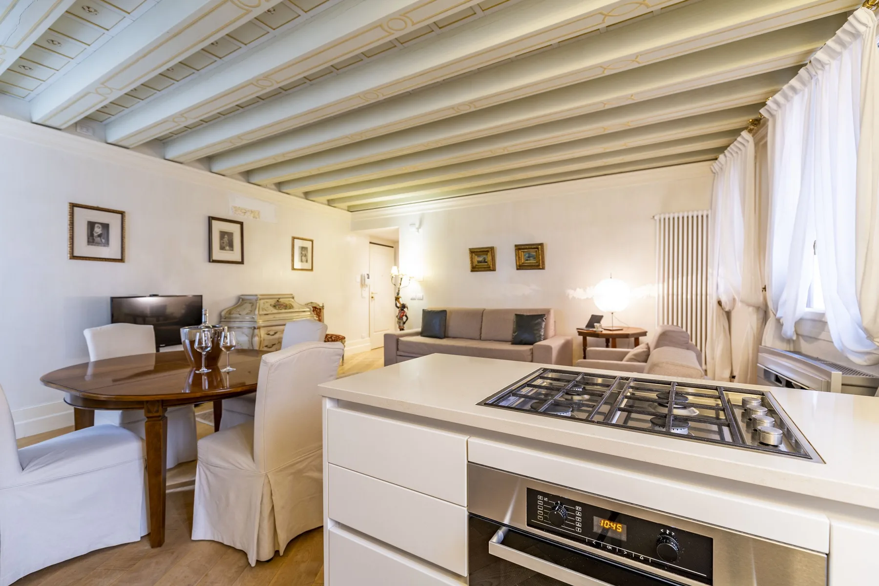 A bright open-plan room combines a kitchen island with a dining table and seating area.