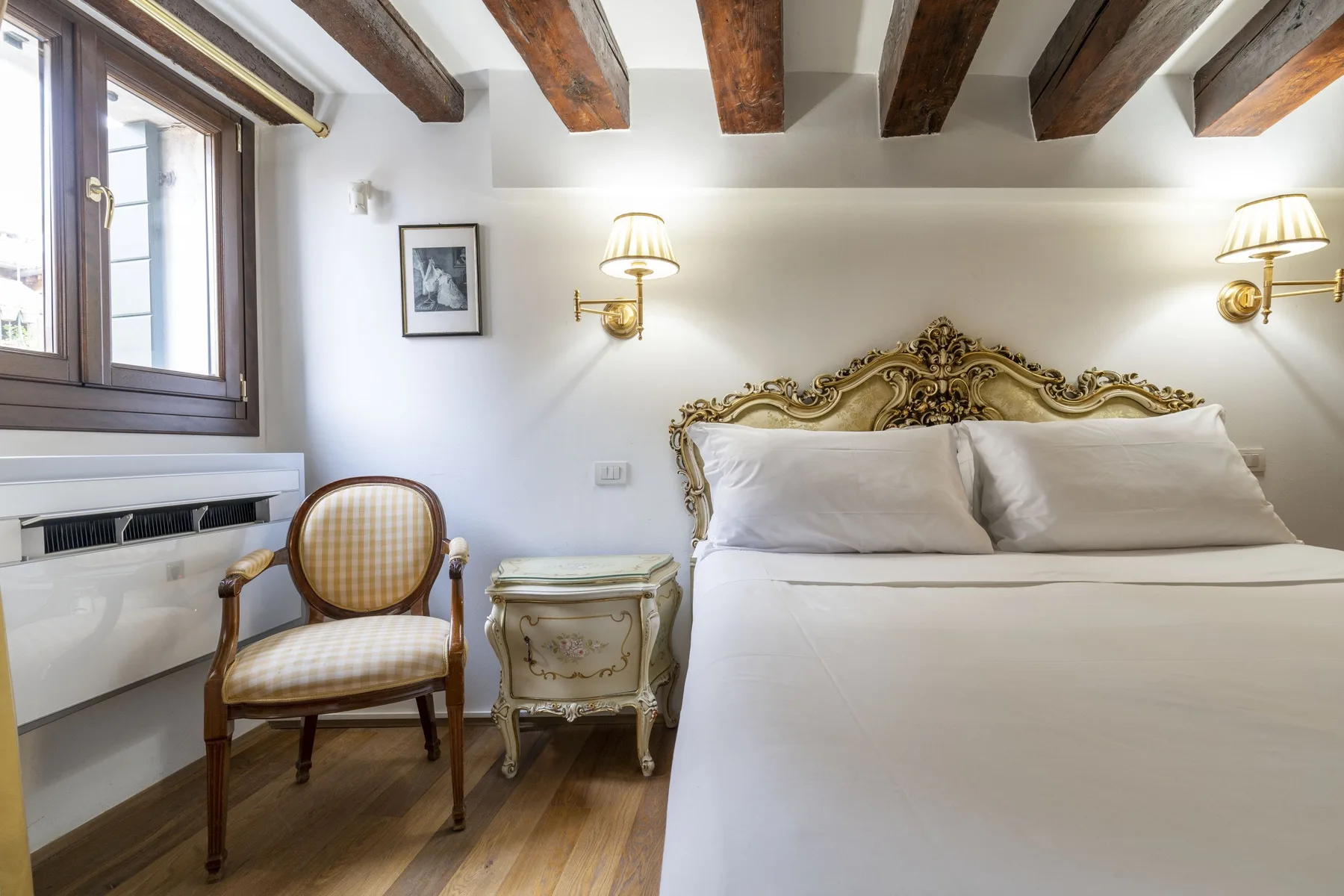 A bedroom with a large bed, a chair, and exposed ceiling beams.