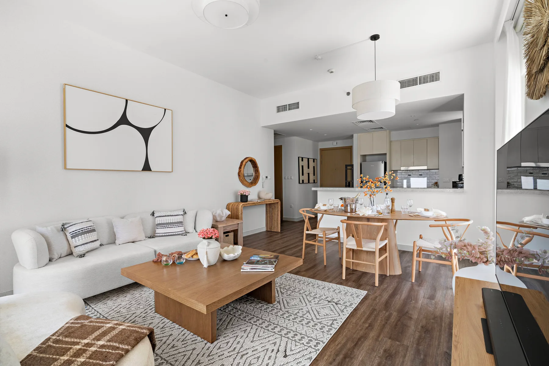 Una luminosa sala de estar y comedor con asientos, una mesa de madera y una cocina abierta.