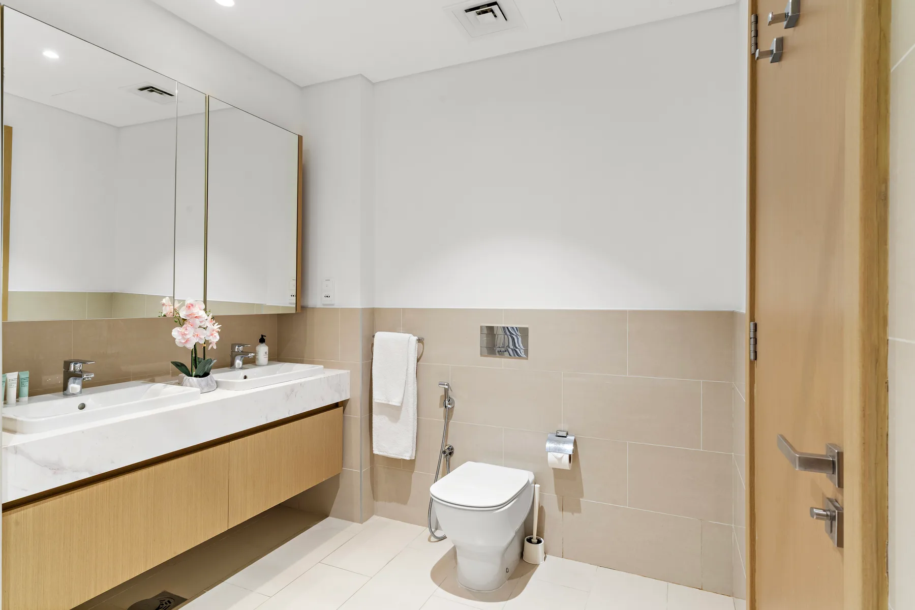 Un baño con un tocador largo, espejo e inodoro.