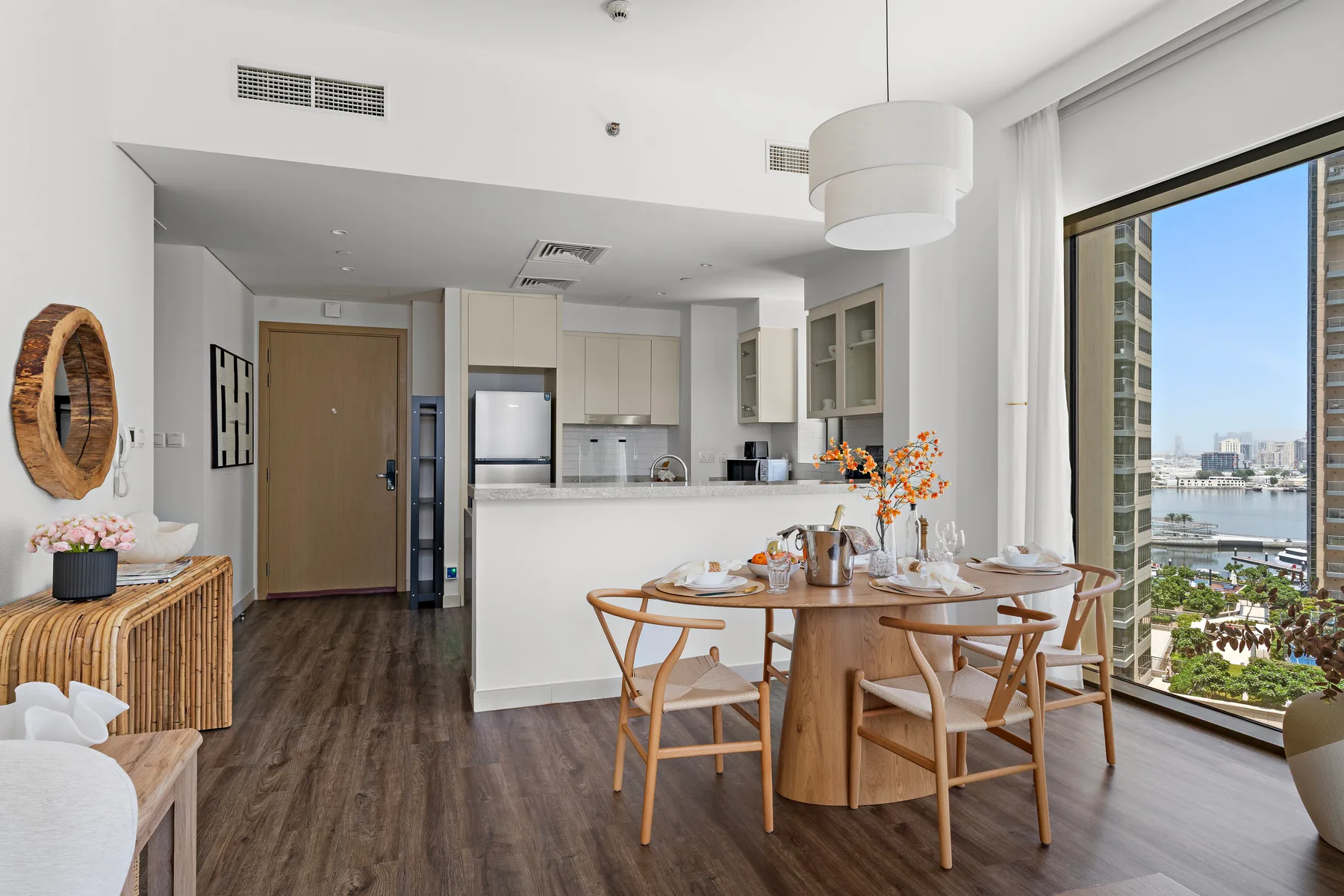 Un comedor diáfano y luminoso con cocina y una mesa junto a grandes ventanales.