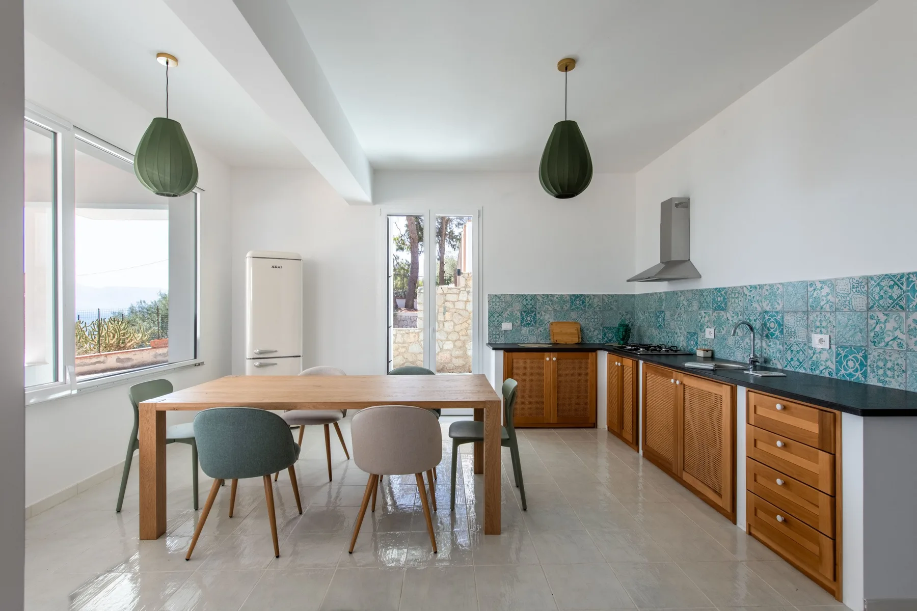 A bright kitchen and dining area with a wooden table beside a tiled counter.