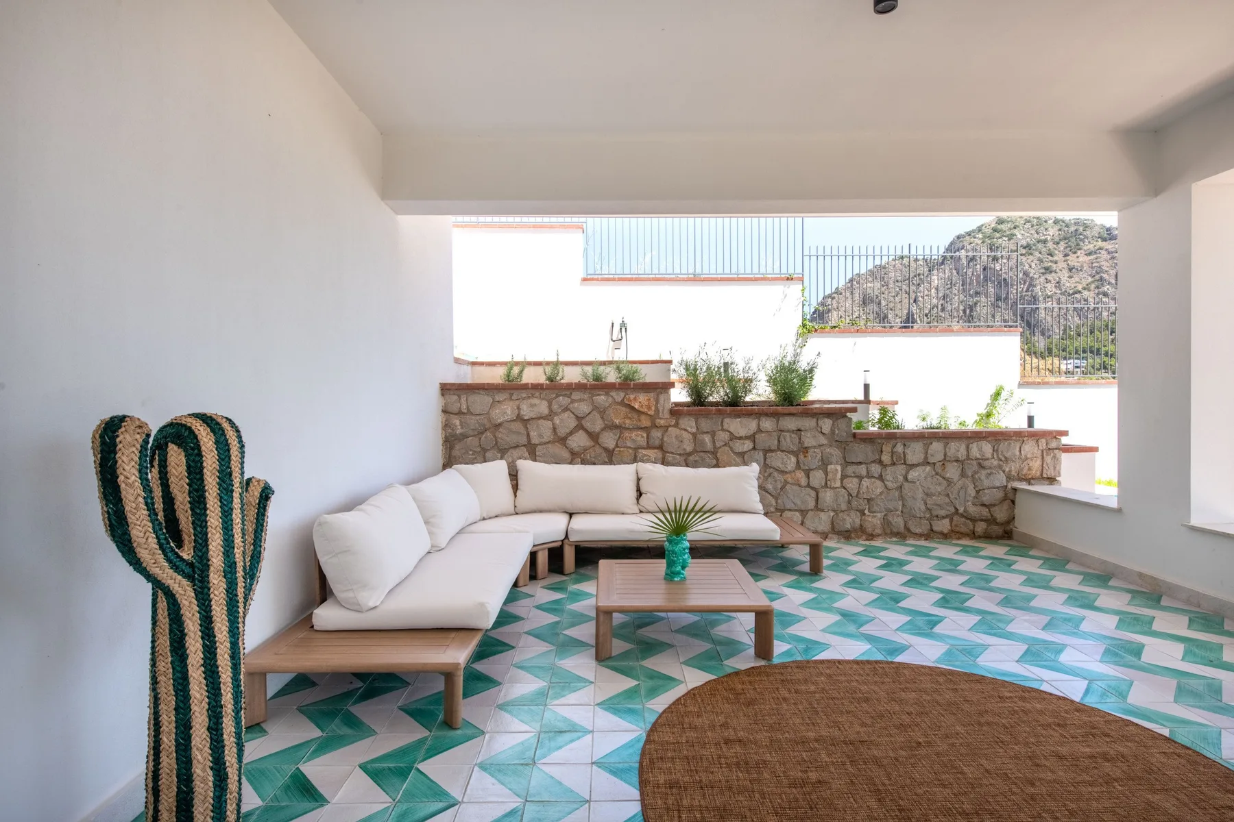 A covered terrace with seating, a low table, and patterned tile flooring.