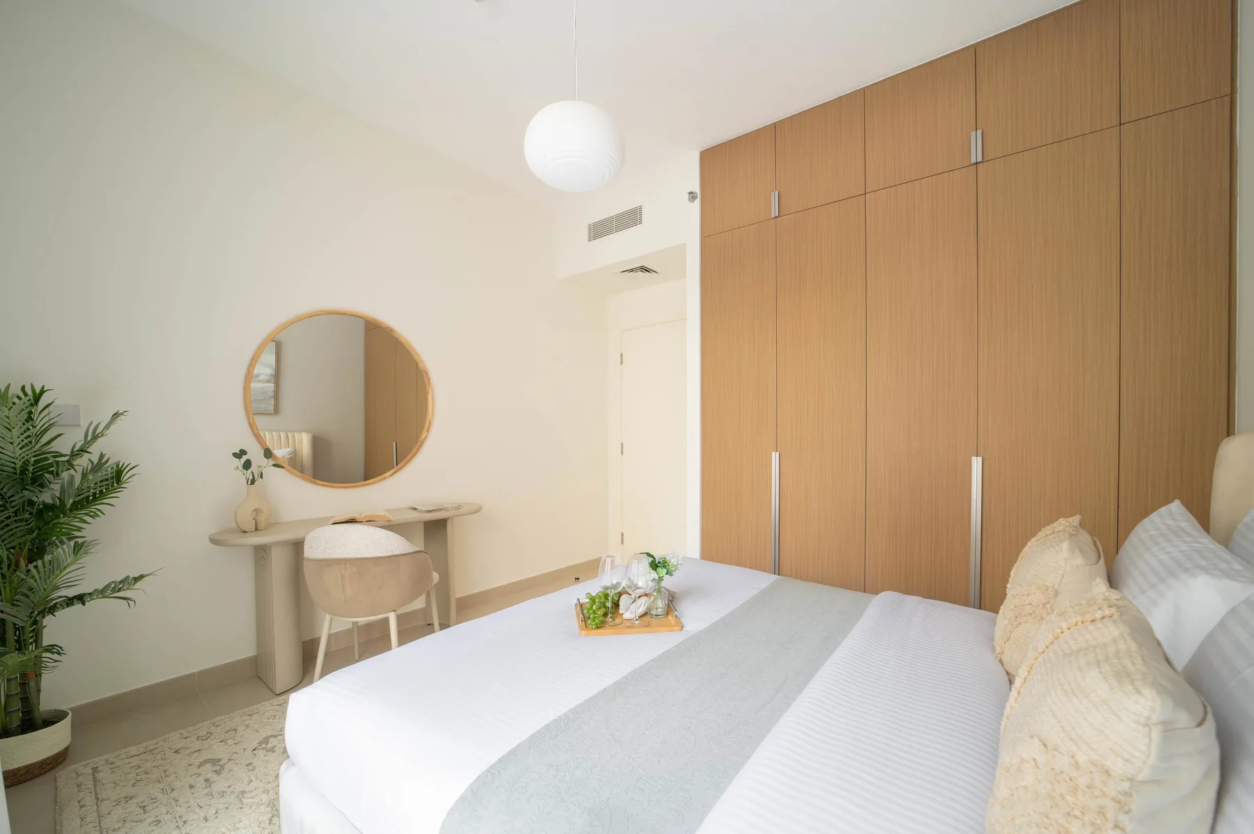 Un dormitorio luminoso con una cama bien hecha y un armario de madera.
