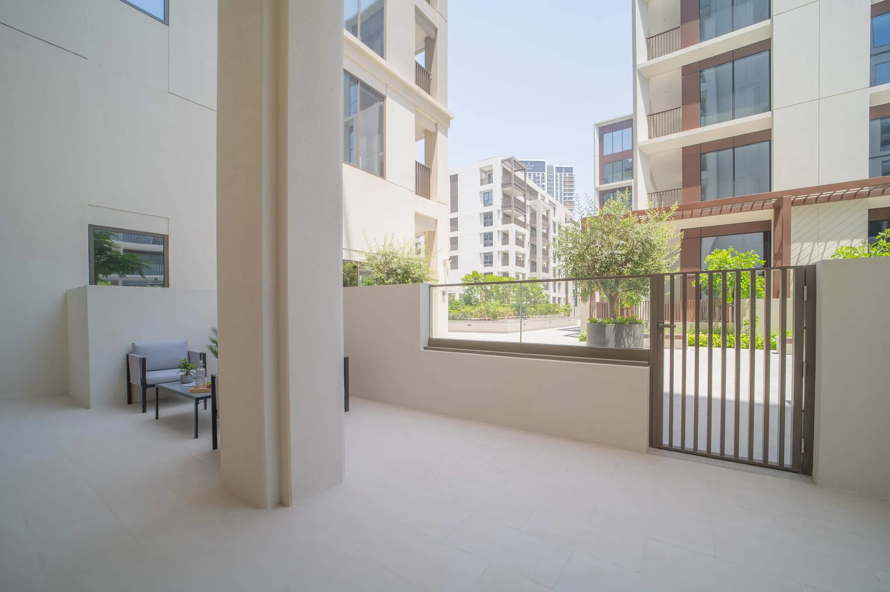 Una terraza luminosa da a edificios de apartamentos modernos, con asientos junto a una baranda con puerta.