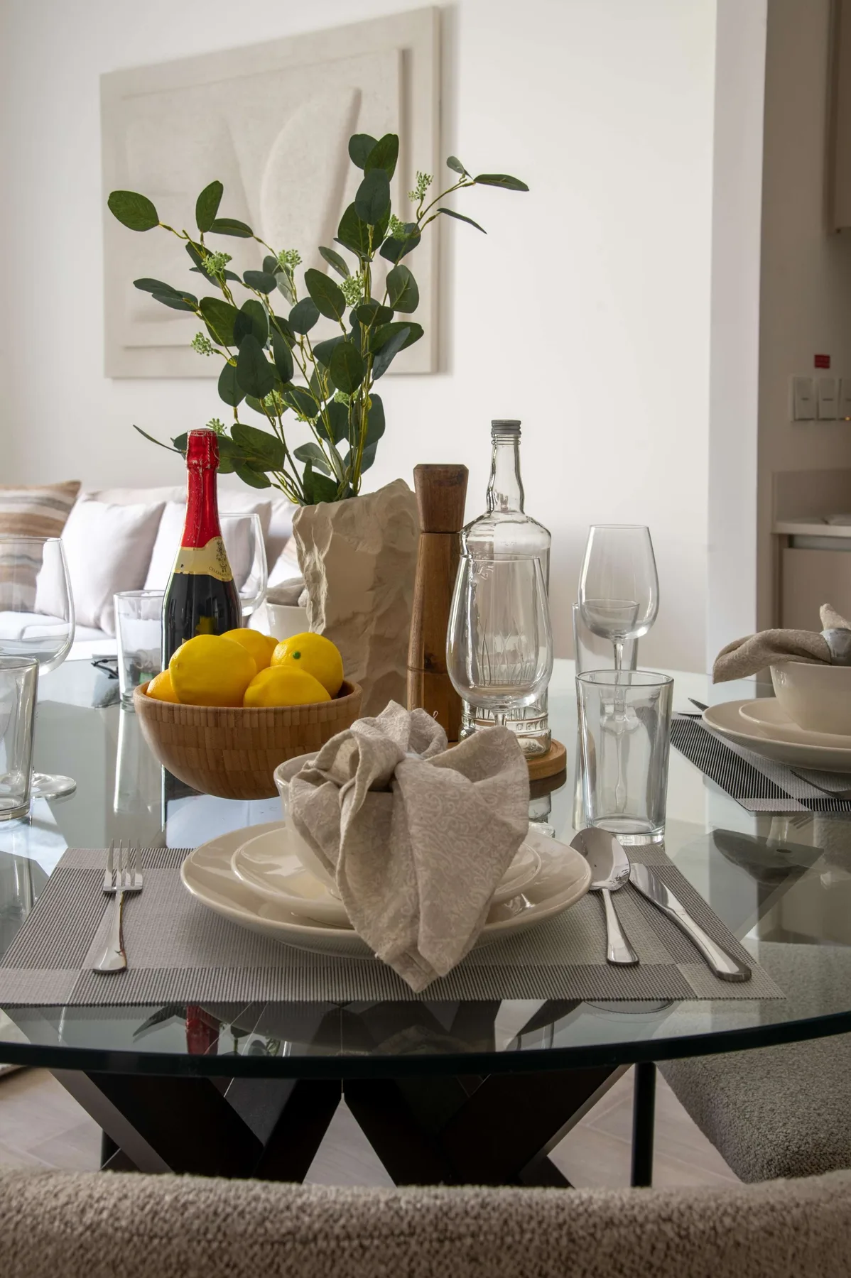 Una mesa de comedor está puesta con platos, vasos y un cuenco de limones.