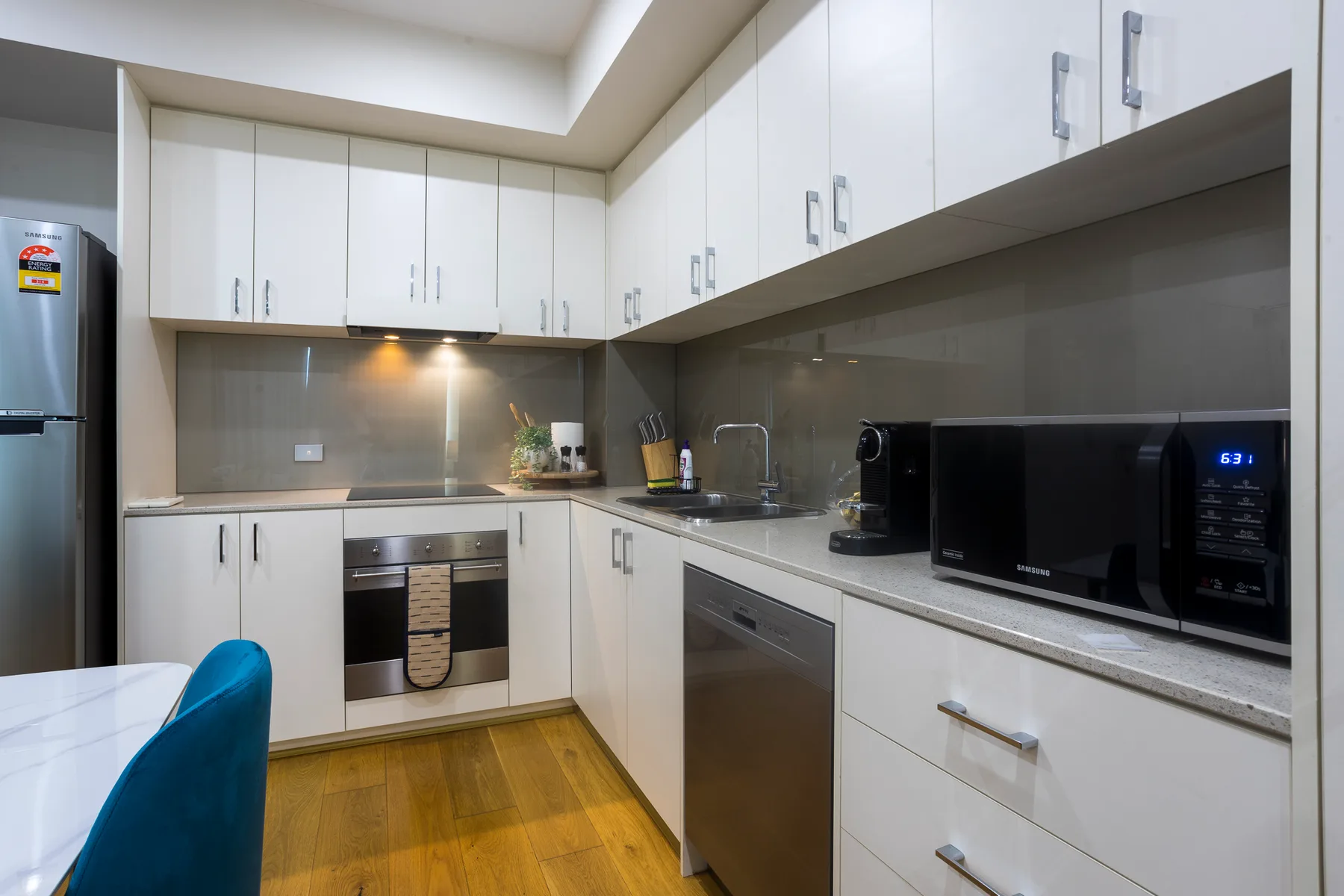 Una cocina moderna con gabinetes blancos, electrodomésticos de acero inoxidable y piso de madera.