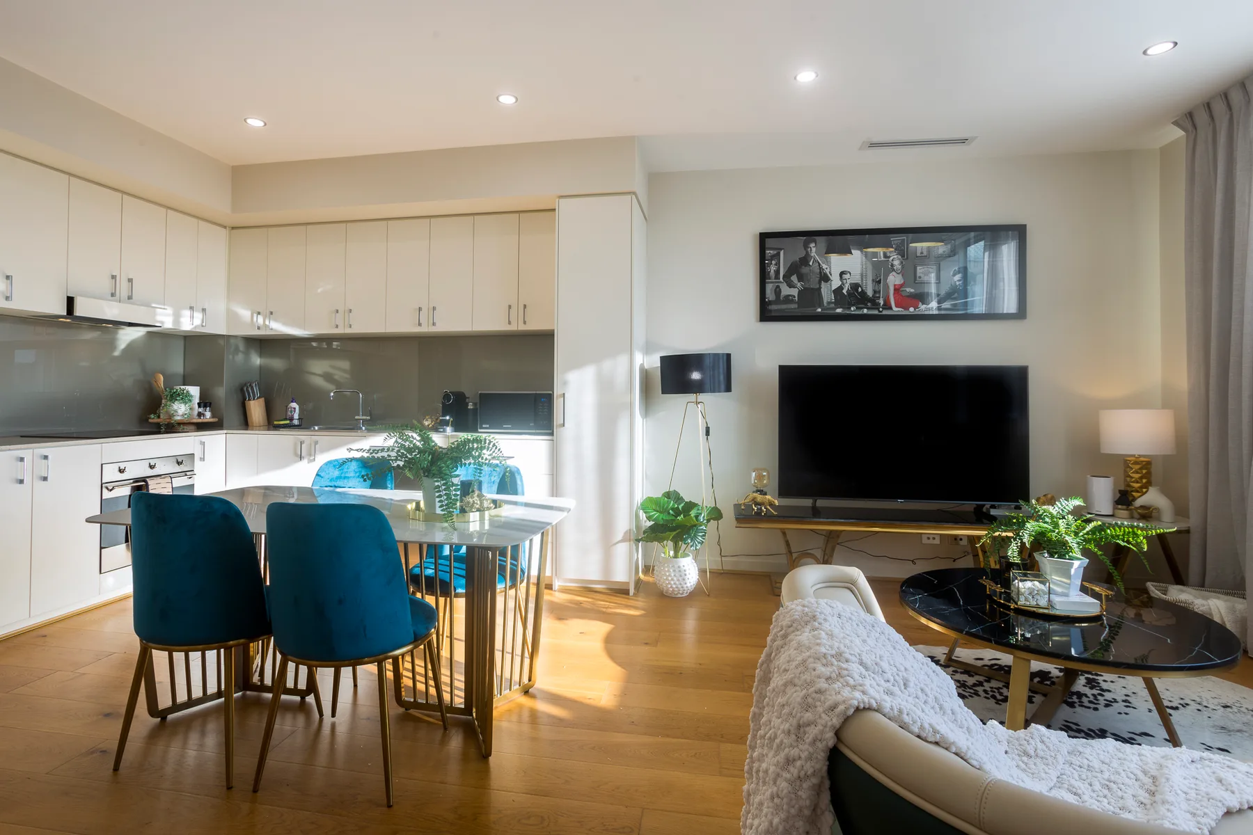 Sala de estar y cocina de planta abierta con una isla de comedor y un televisor.